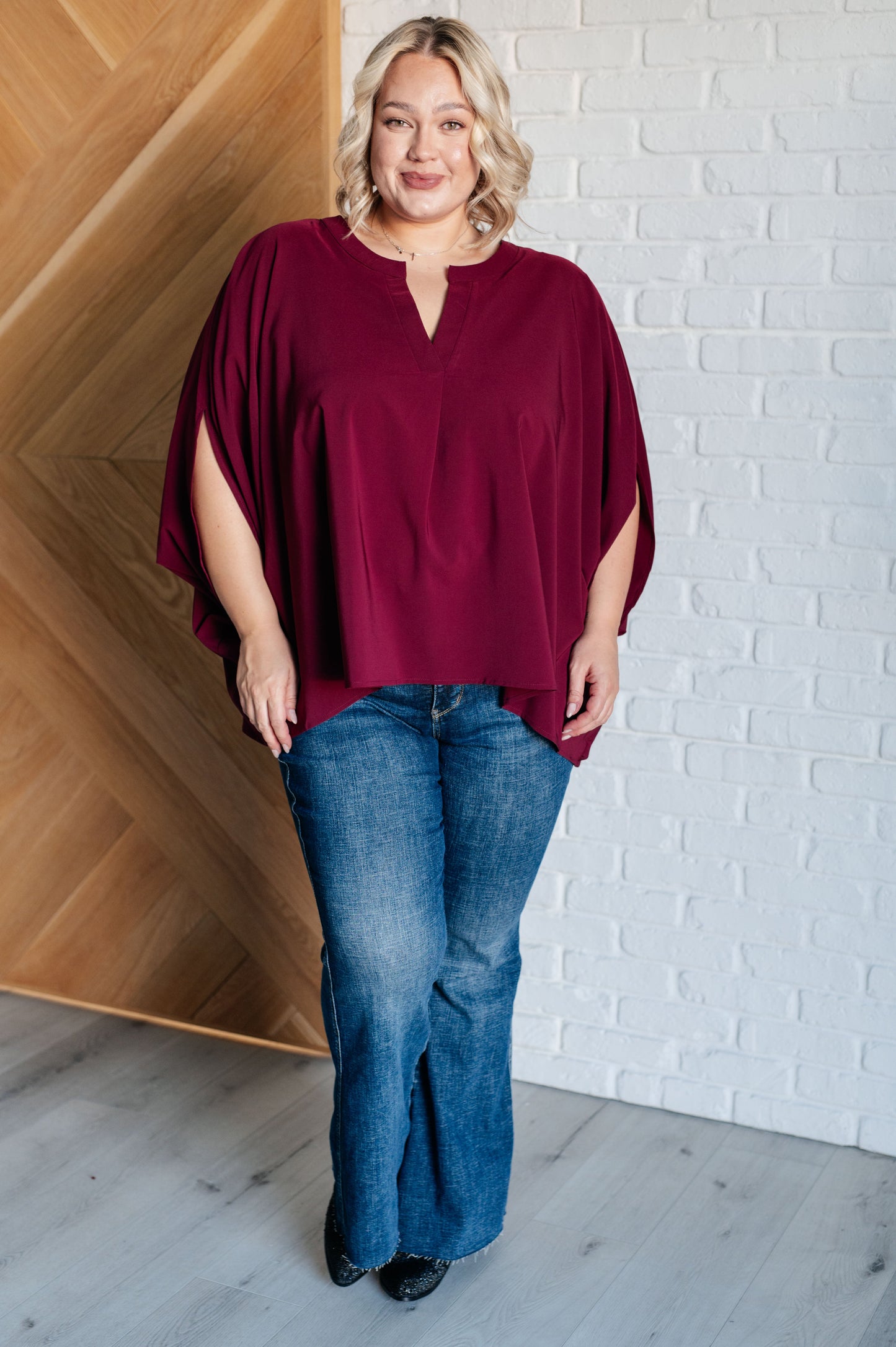 Women's wine-colored poncho-style blouse with a Gabby V-neckline, batwing sleeves, and an oversized fit, made from lightweight woven fabric.