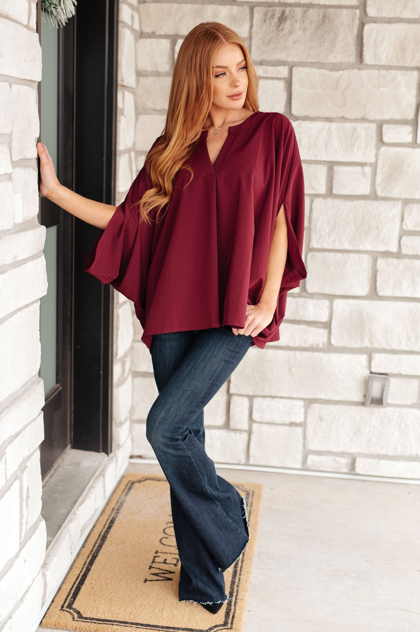 Women's wine-colored poncho-style blouse with a Gabby V-neckline, batwing sleeves, and an oversized fit, made from lightweight woven fabric.