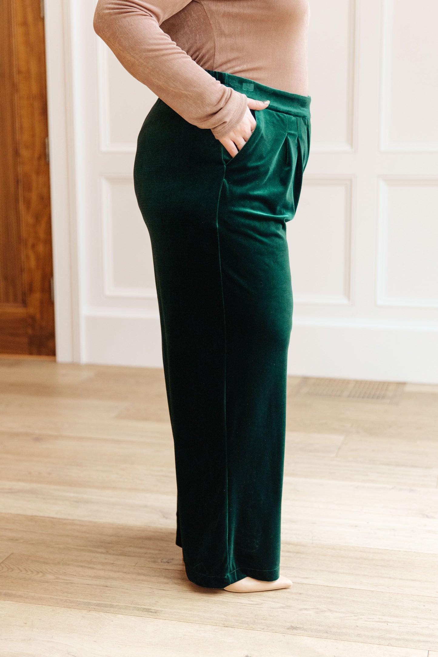 Side view of the plus size high-rise velvet trousers with pockets and zip fly – emerald.
