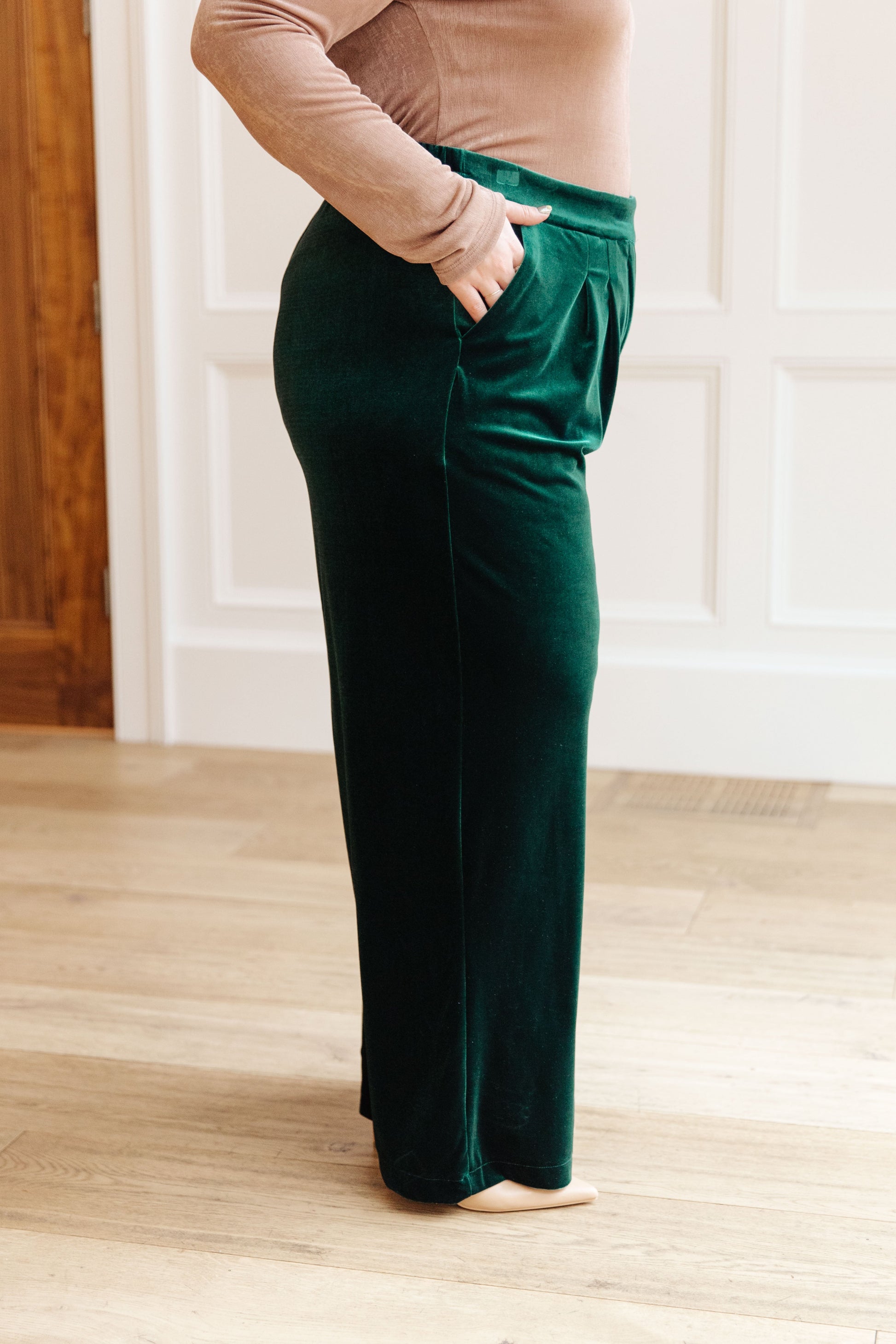 Side view of the plus size high-rise velvet trousers with pockets and zip fly – emerald.

