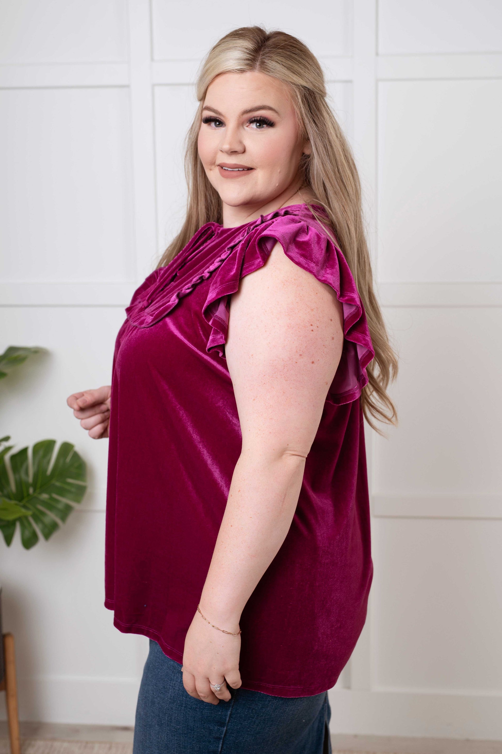  Women's blouse in soft magenta velvet with a keyhole tie neckline, flutter sleeves, gathered bust, and ruffle details. Perfect for special occasions.