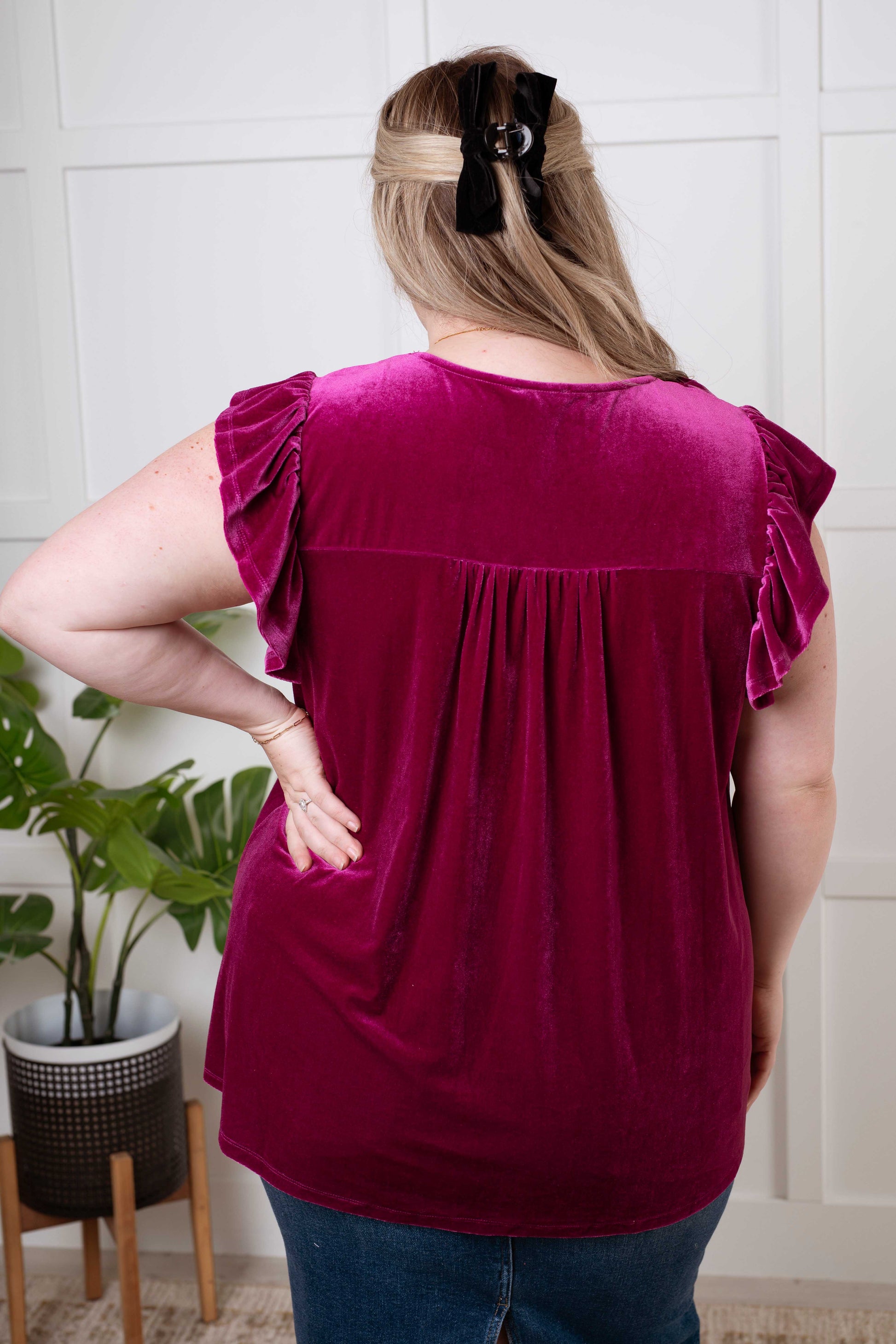  Women's blouse in soft magenta velvet with a keyhole tie neckline, flutter sleeves, gathered bust, and ruffle details. Perfect for special occasions.