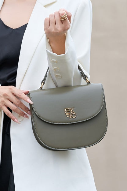 Woman holding olive Heloise Crossbody Bag by top handle in crook of arm.