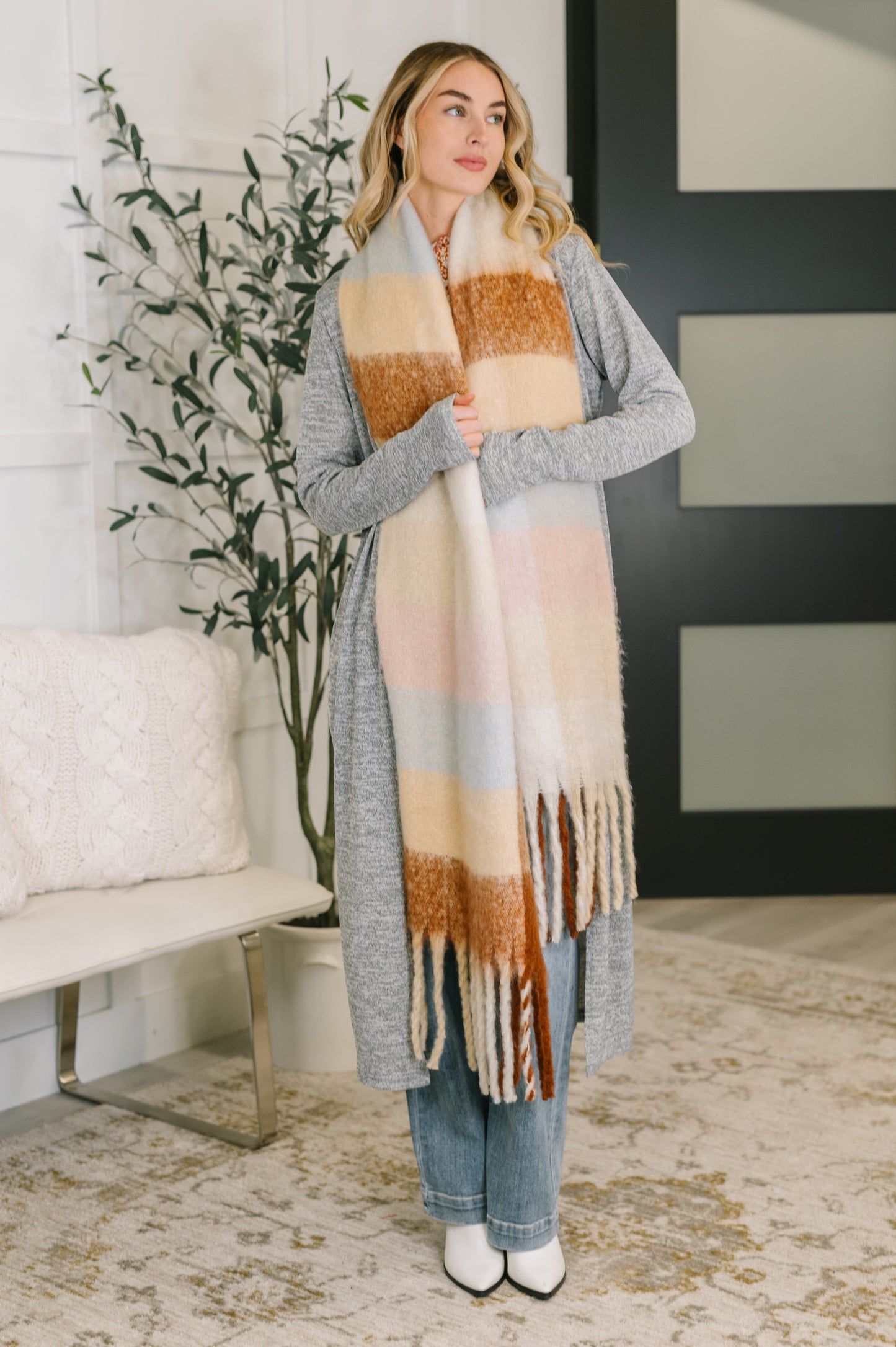 Model wearing the Wanderlust Wrap Oversized Plaid Fringe Scarf in light brown.
