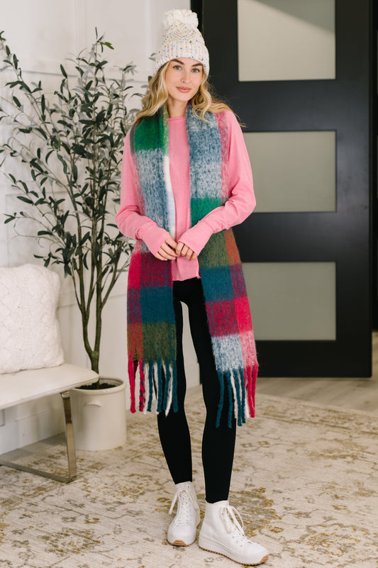 Model wearing Wanderlust Wrap Oversized Plaid Fringe Scarf in magenta and teal.