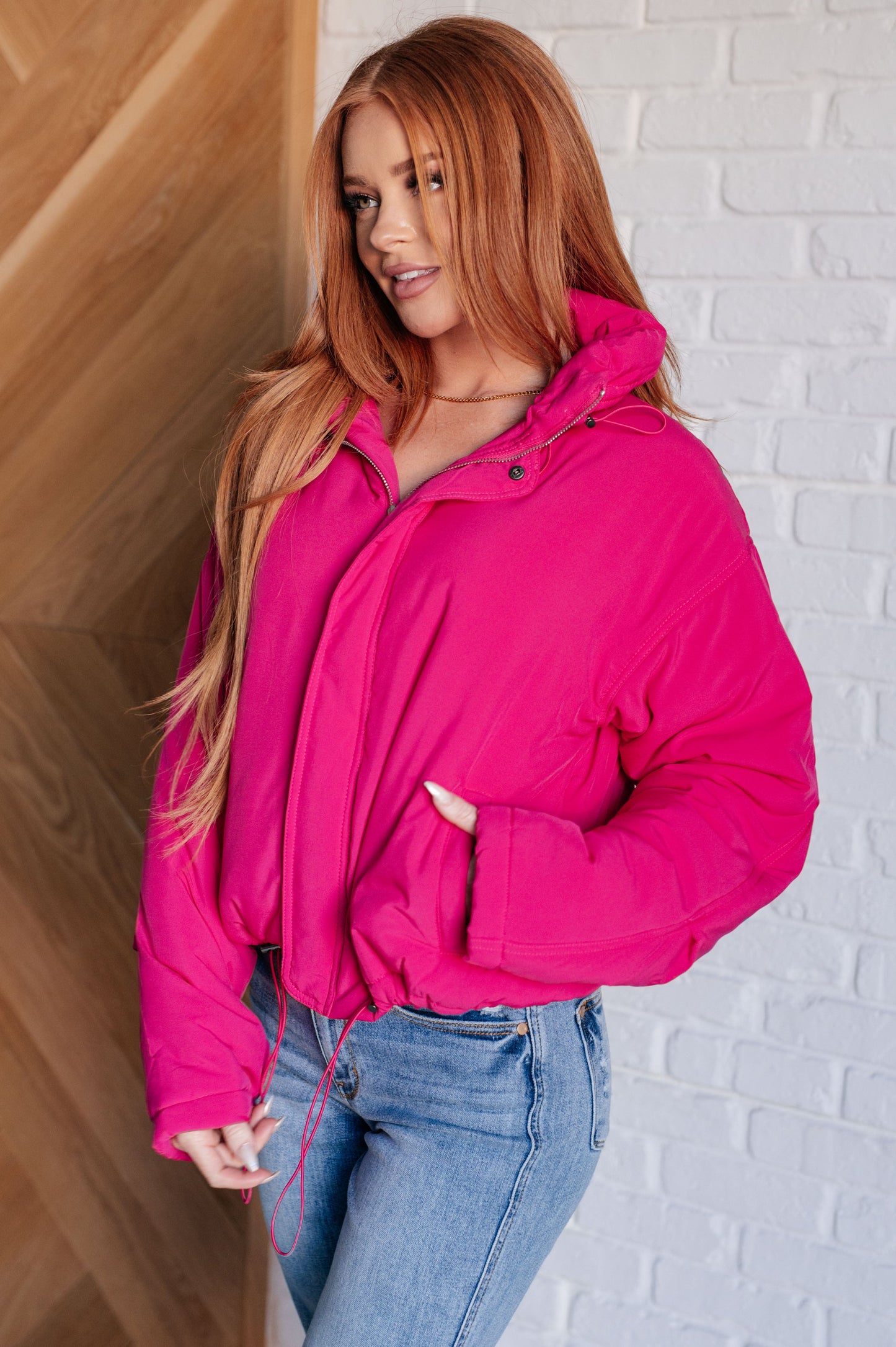 A women's hot pink puffer jacket with a quilted design, zip and snap front closure, two front pockets, toggled elastic waistband, and neckline for a snug fit.