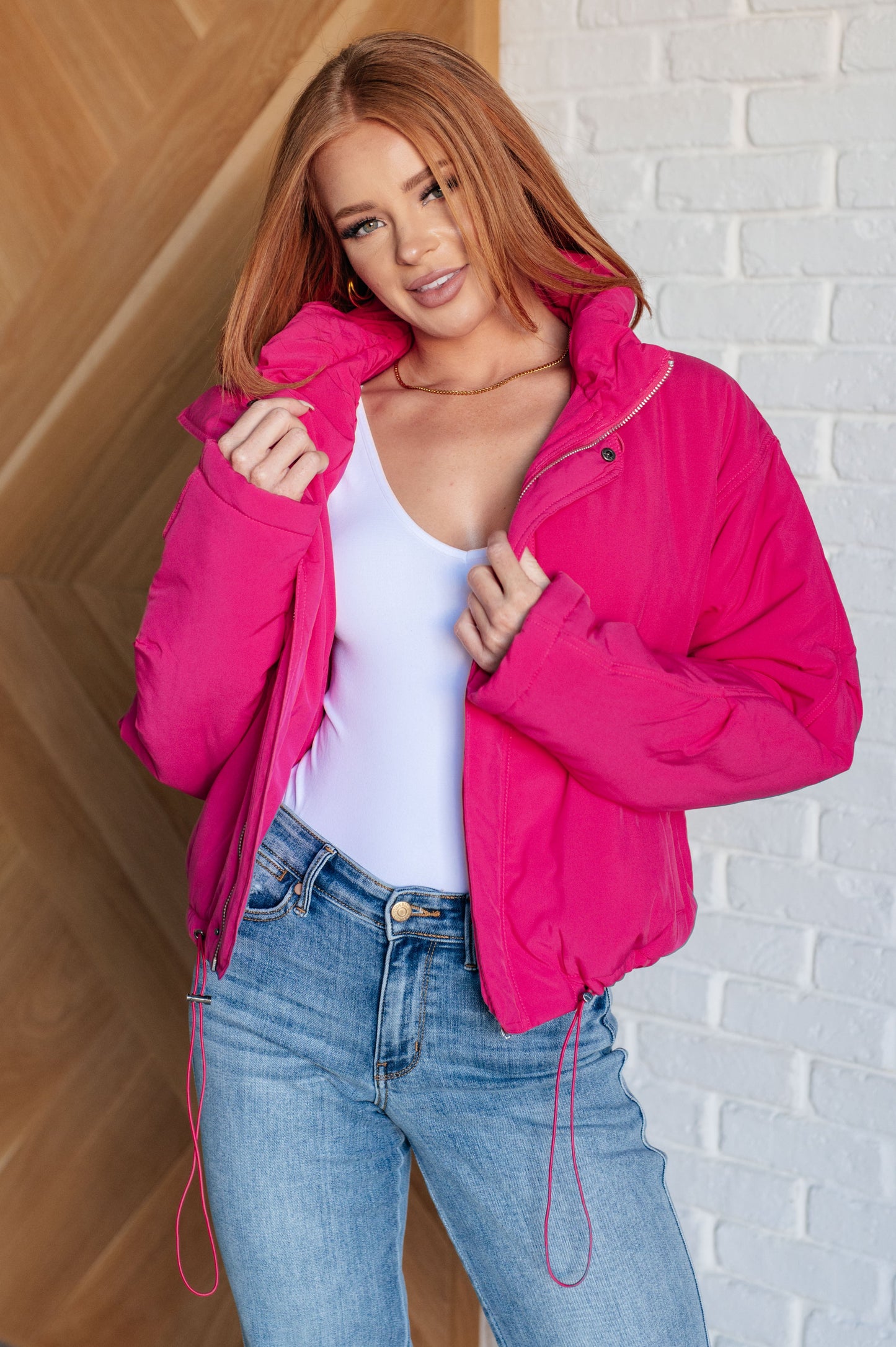 A women's hot pink puffer jacket with a quilted design, zip and snap front closure, two front pockets, toggled elastic waistband, and neckline for a snug fit.