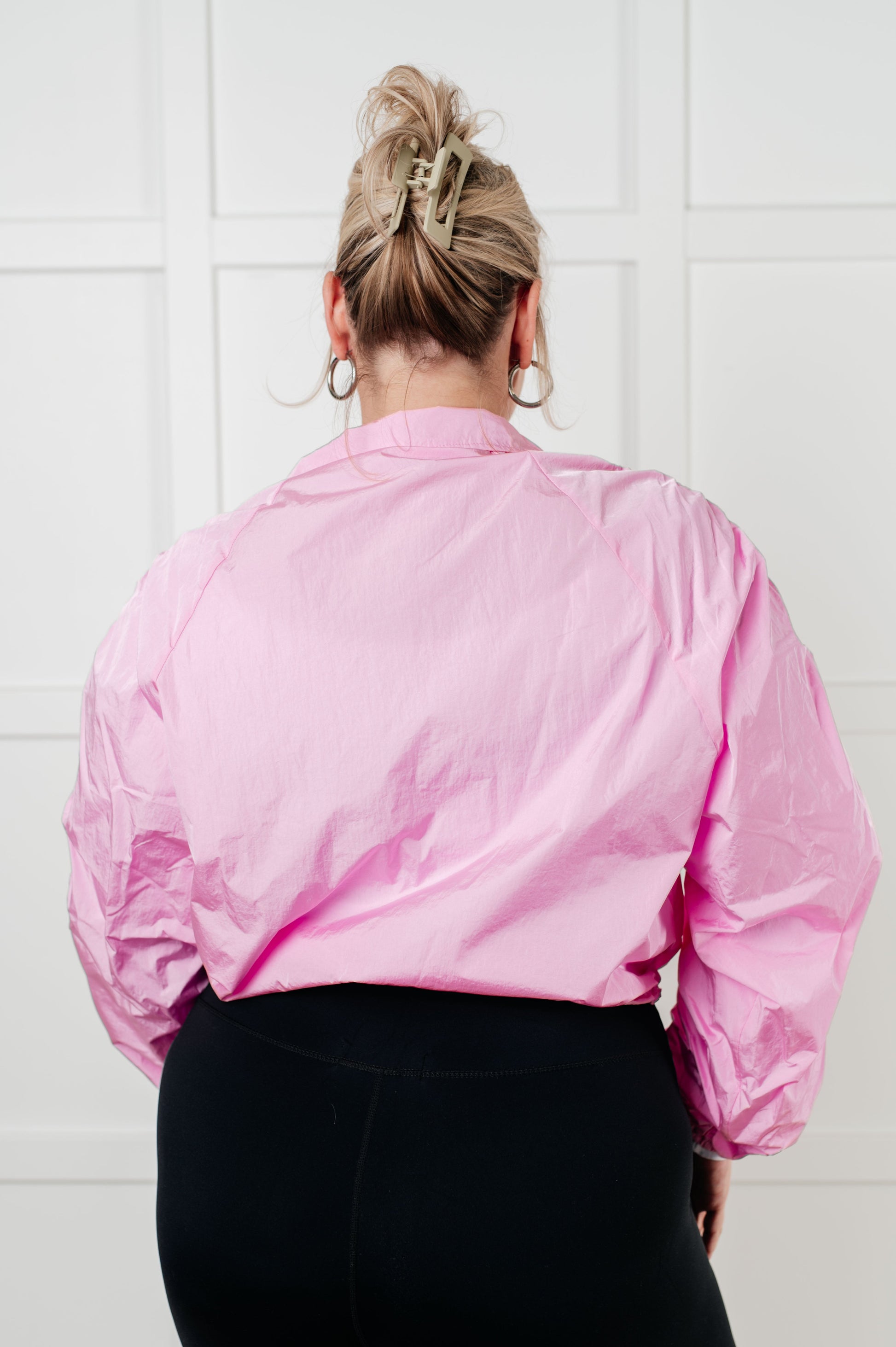 Women's pink windbreaker featuring ruched sleeves, chic collar, front zipper, adjustable hemline, and front pockets, designed for style and practicality.