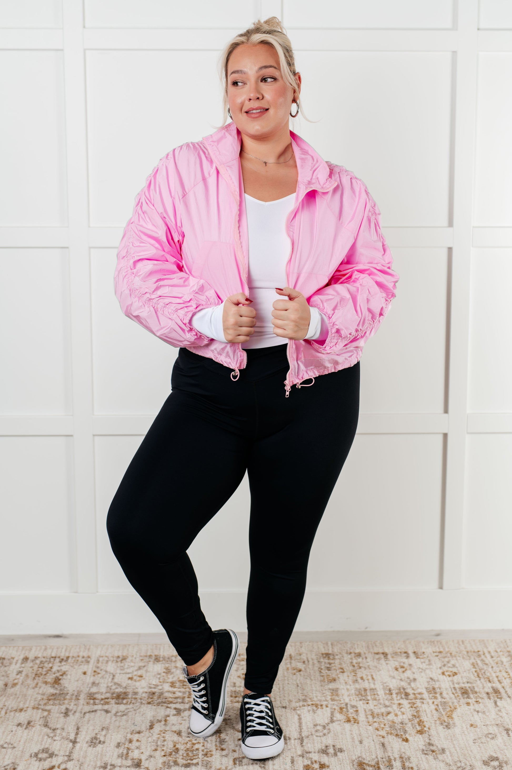 Women's pink windbreaker featuring ruched sleeves, chic collar, front zipper, adjustable hemline, and front pockets, designed for style and practicality.