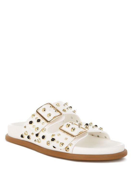 White stud embellished sliders with pin buckle strap closure and platform flat heel.