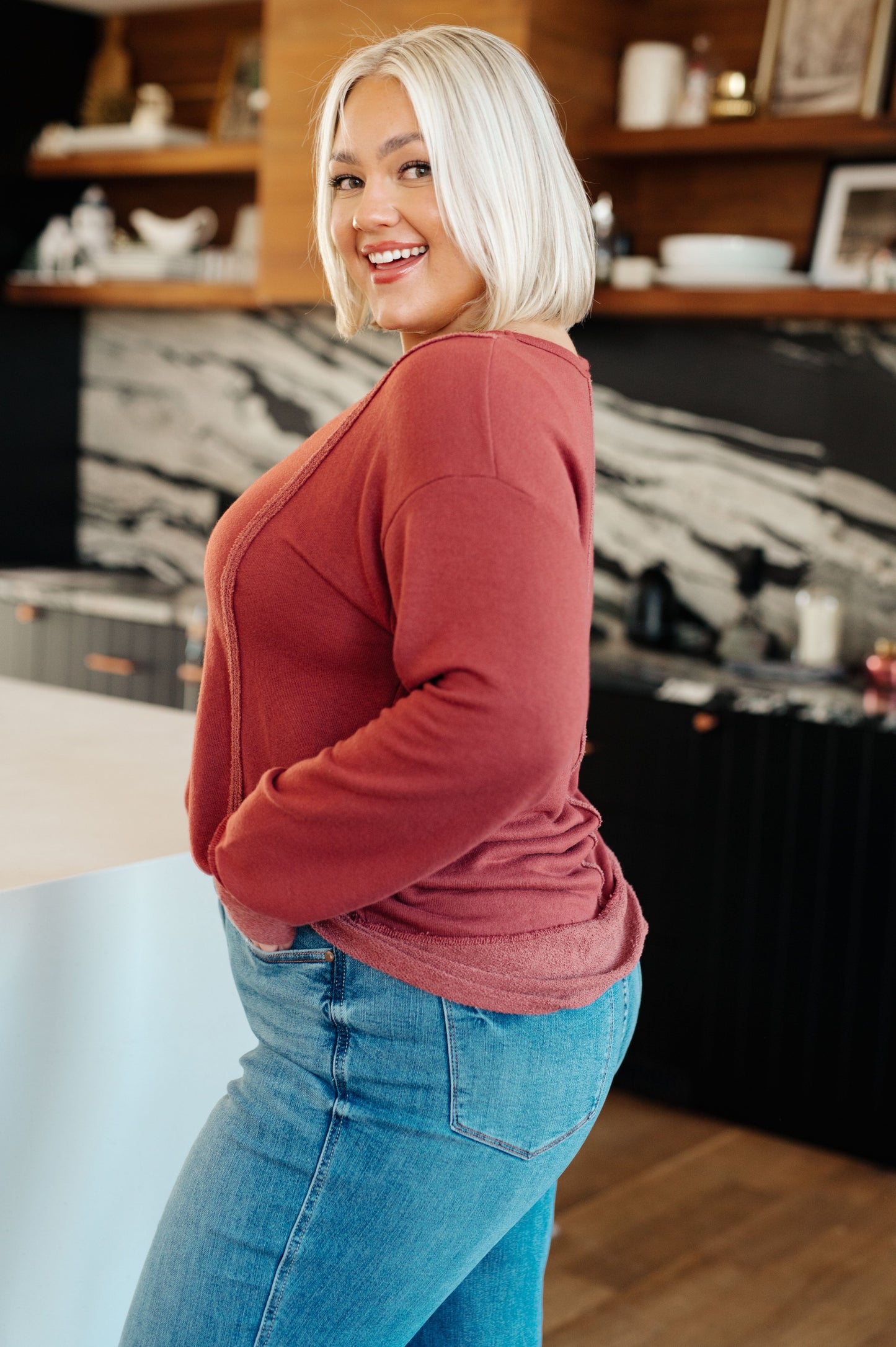 Plus size side view of Taya Pullover with dropped shoulders and stepped hem in red French terry fabric.