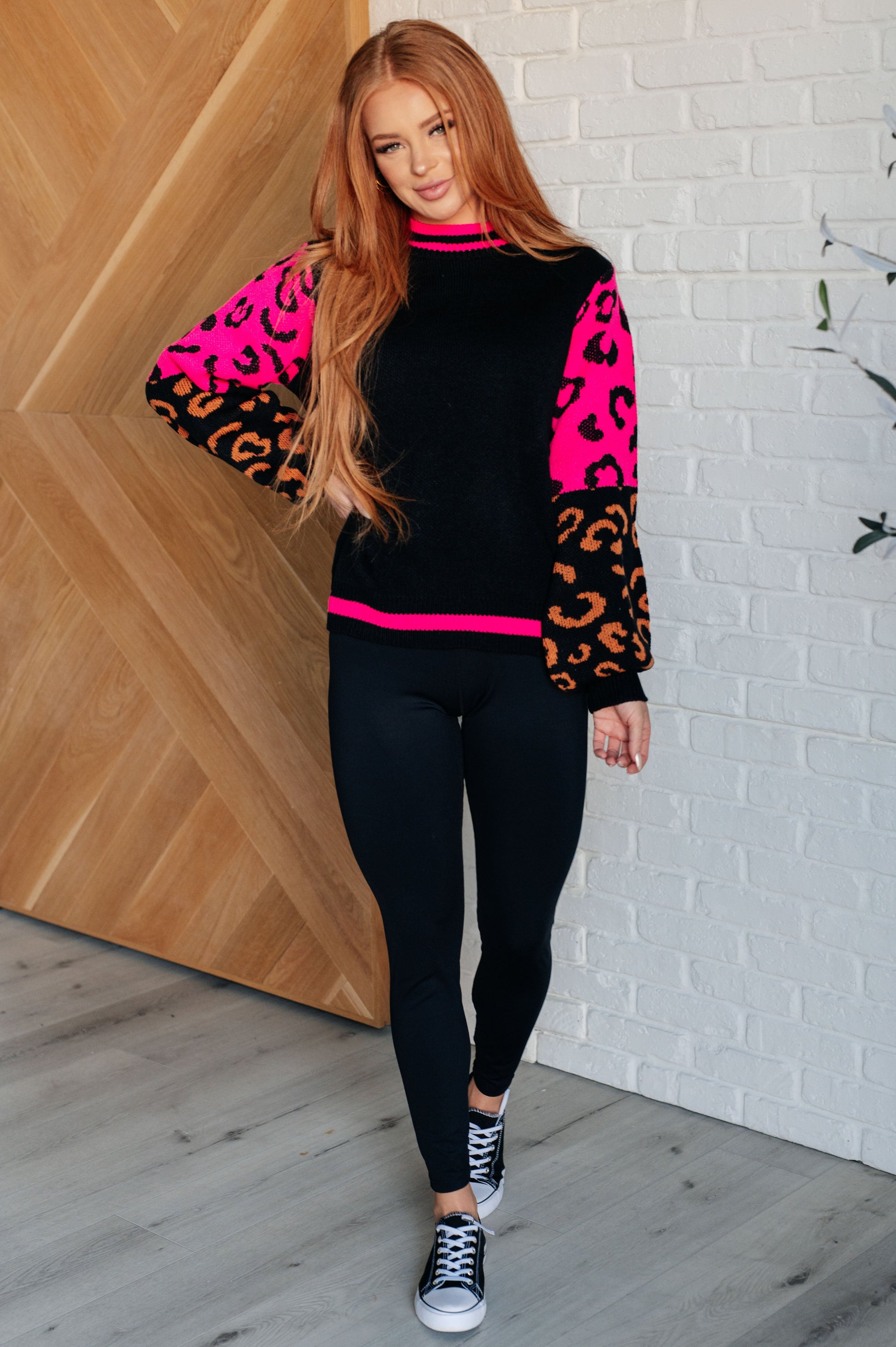 Women's animal print sweater with color block design and pink contrast details.