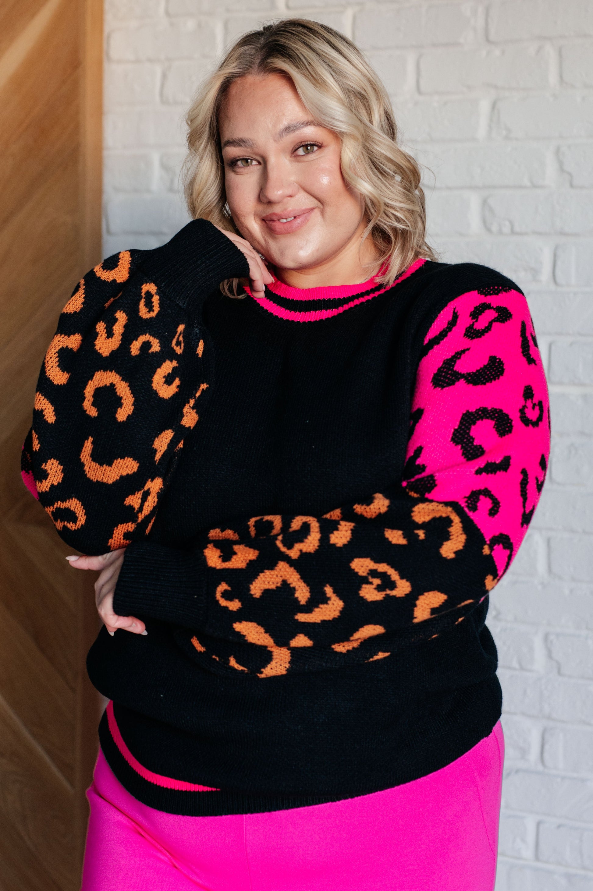 Women's animal print sweater with color block design and pink contrast details.