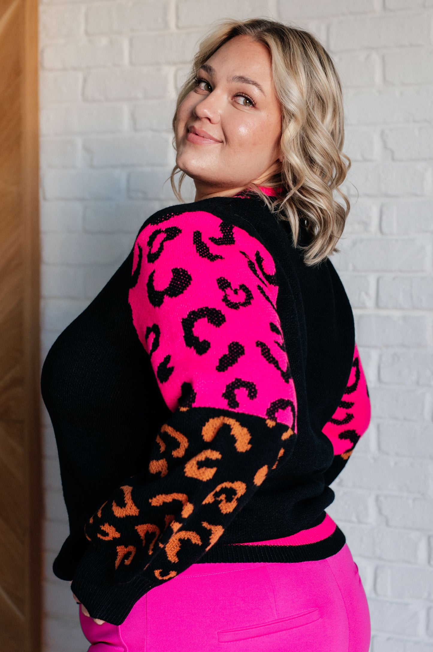 Women's animal print sweater with color block design and pink contrast details.