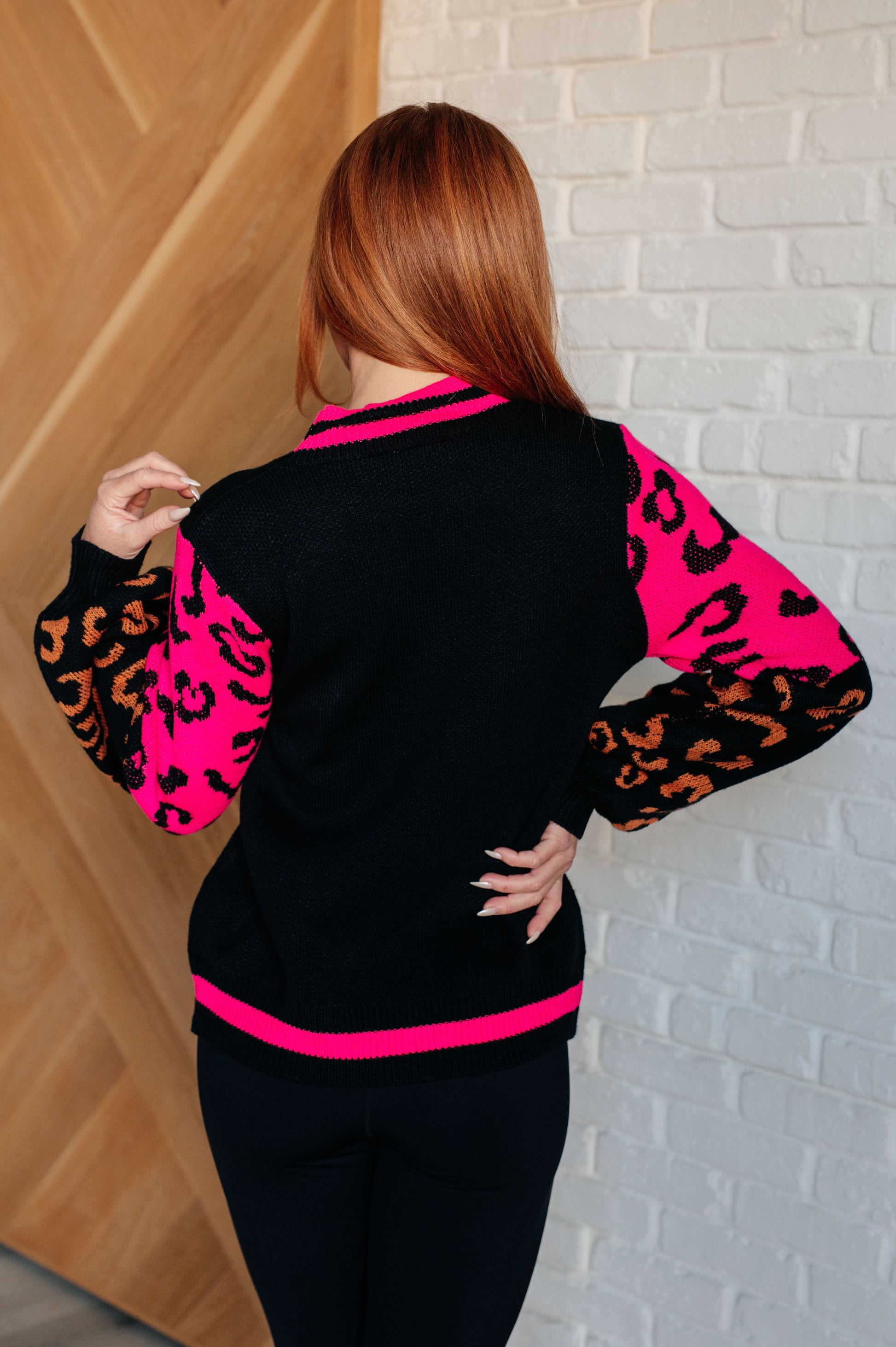 Women's animal print sweater with color block design and pink contrast details.