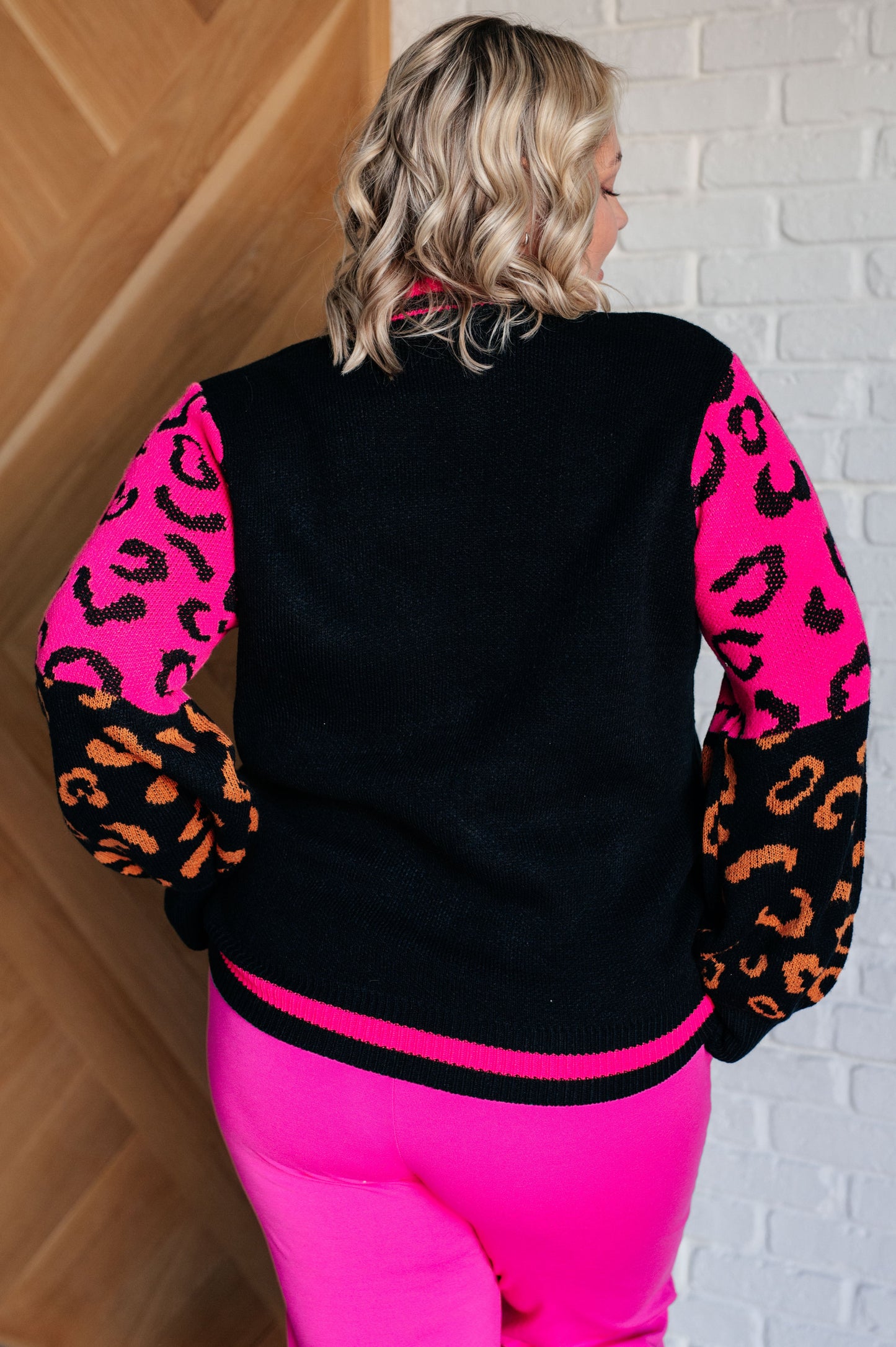 Women's animal print sweater with color block design and pink contrast details.