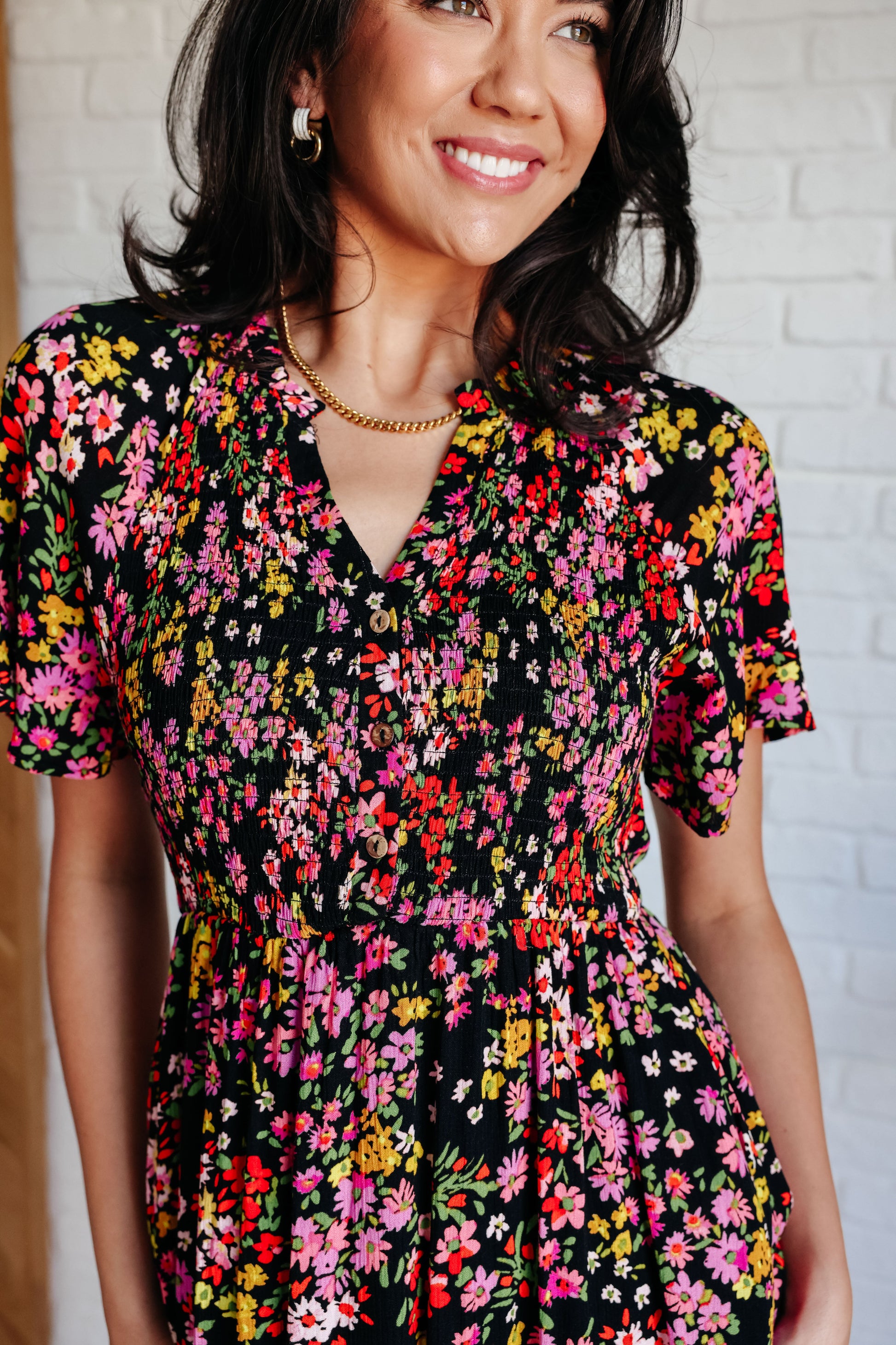 Floral V-neck button-up dress with flutter sleeves, a smocked elastic bodice, an elastic waistline, and functional side pockets.