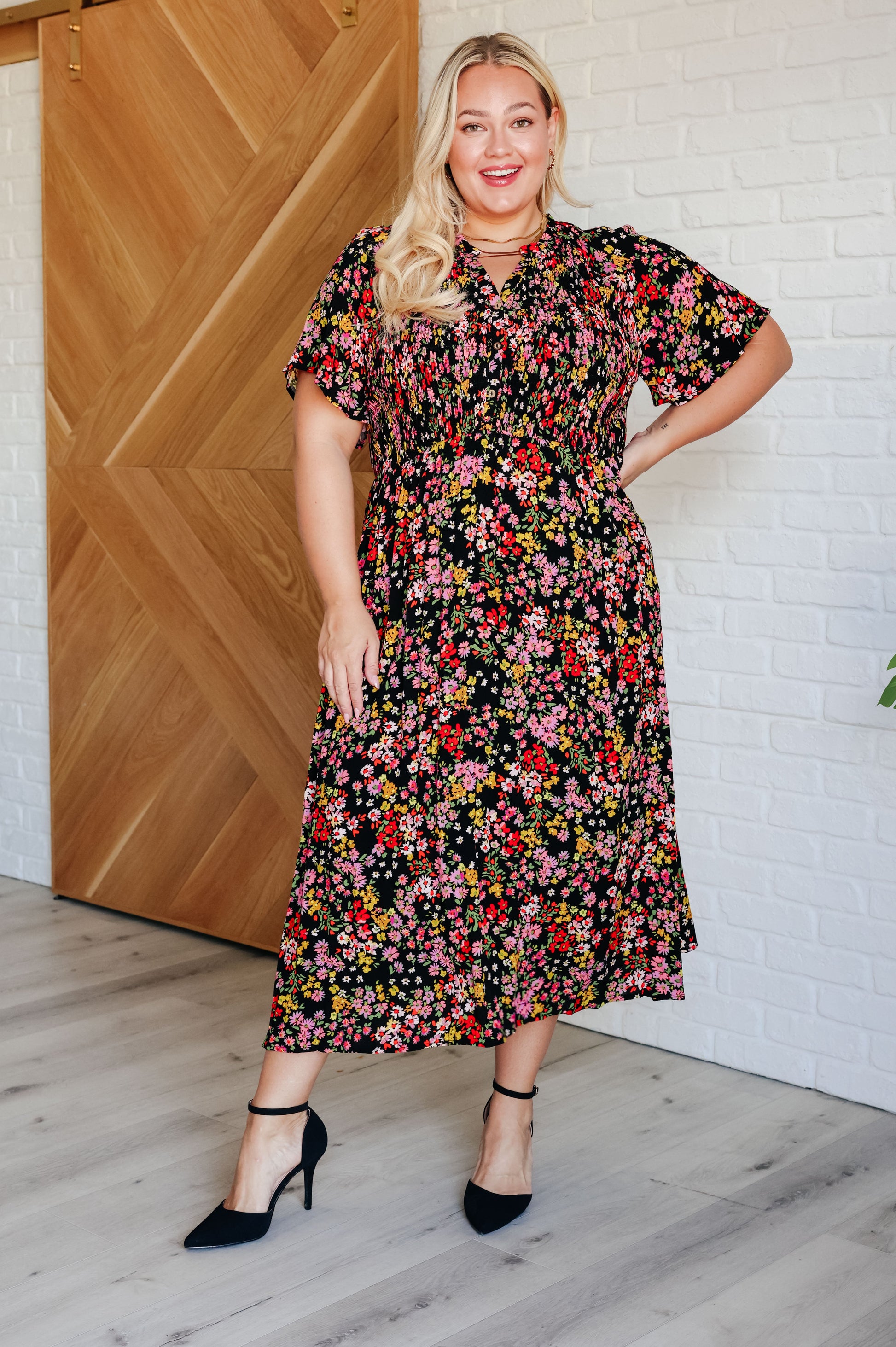 Floral V-neck button-up dress with flutter sleeves, a smocked elastic bodice, an elastic waistline, and functional side pockets.