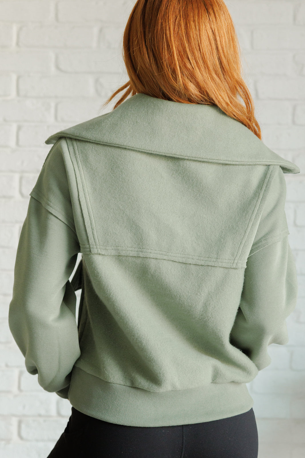 Sage fleece pullover with a collared neckline, half zipper, snap pockets, and raw edge details.