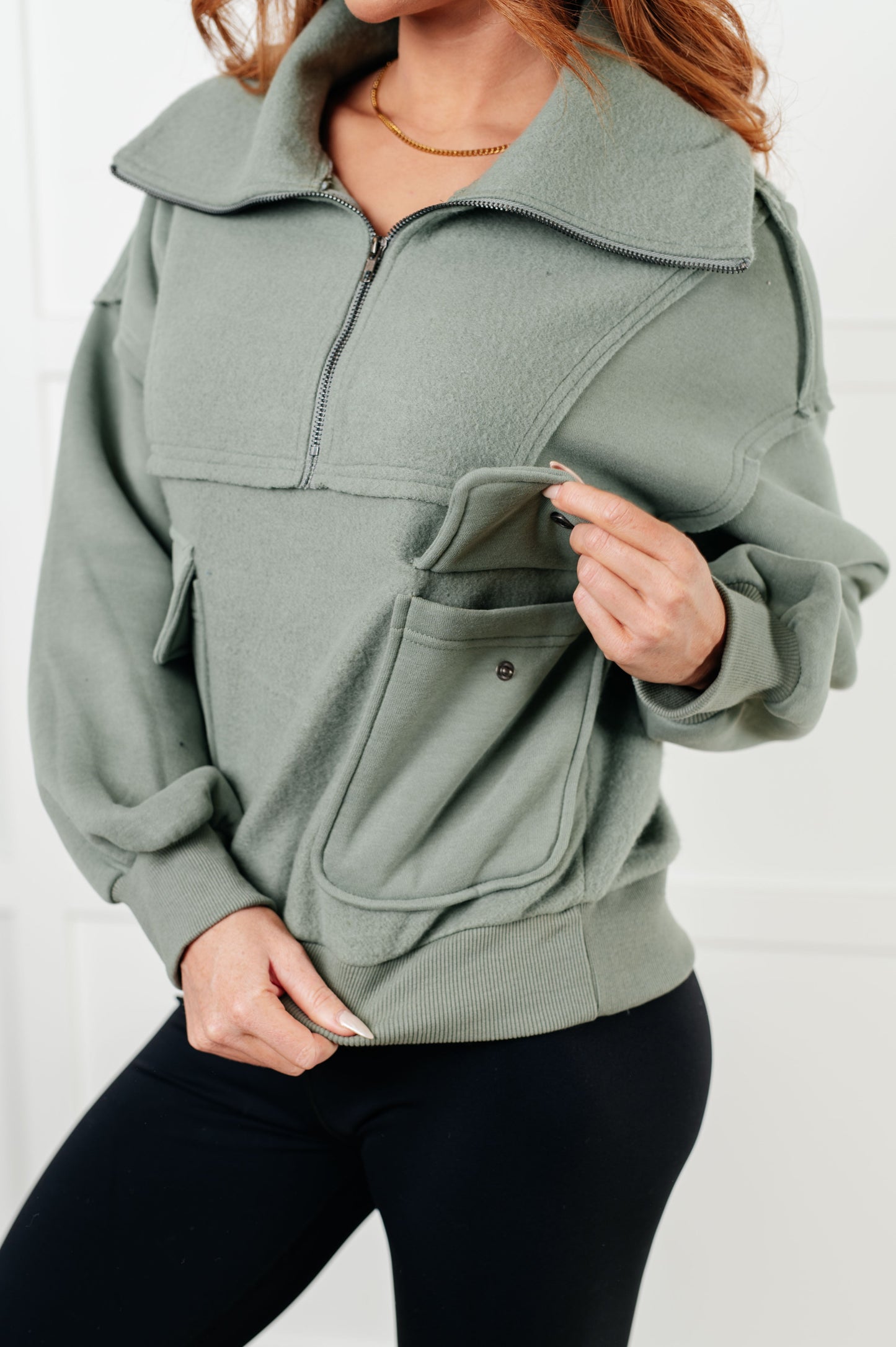 Sage fleece pullover with a collared neckline, half zipper, snap pockets, and raw edge details.