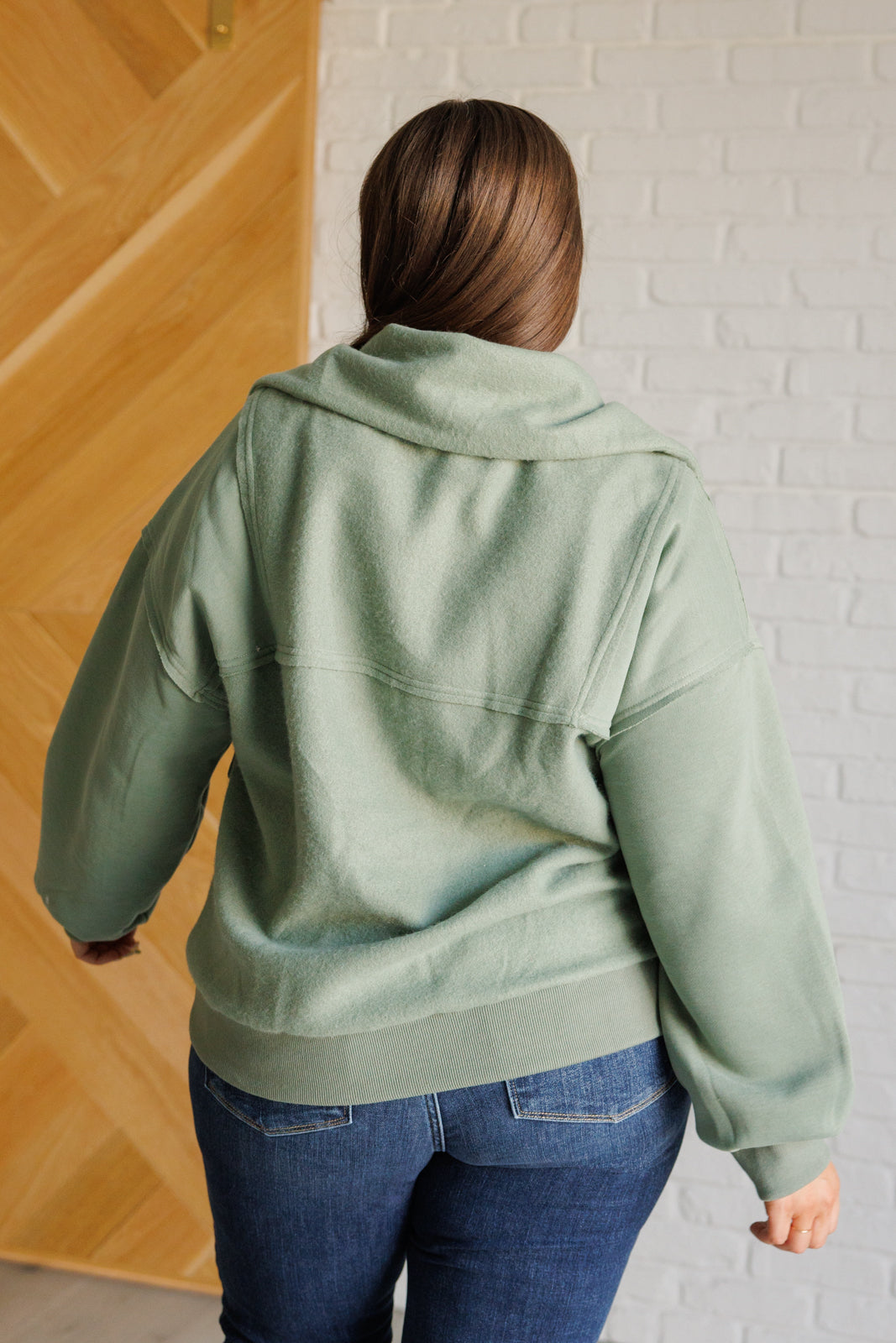 Sage fleece pullover with a collared neckline, half zipper, snap pockets, and raw edge details.