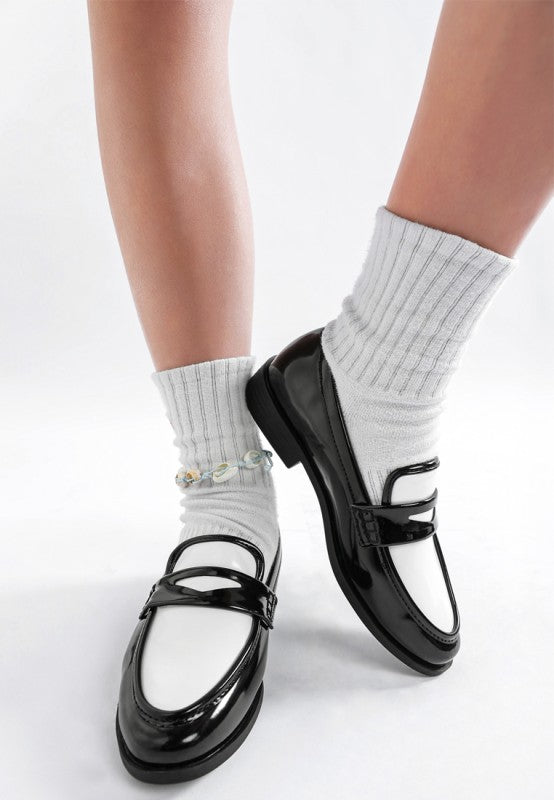 Glossy black-and-white penny loafers with 1-inch block heel and polished finish front view