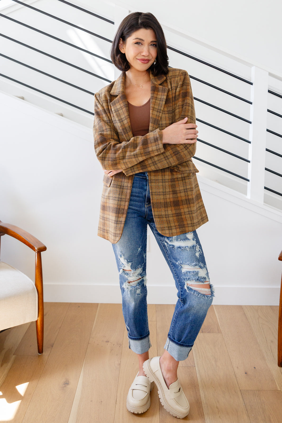 Brown plaid blazer with notched lapels, single button closure, and flap pockets. Features shoulder pads, a fully lined interior, and a tailored, relaxed fit.