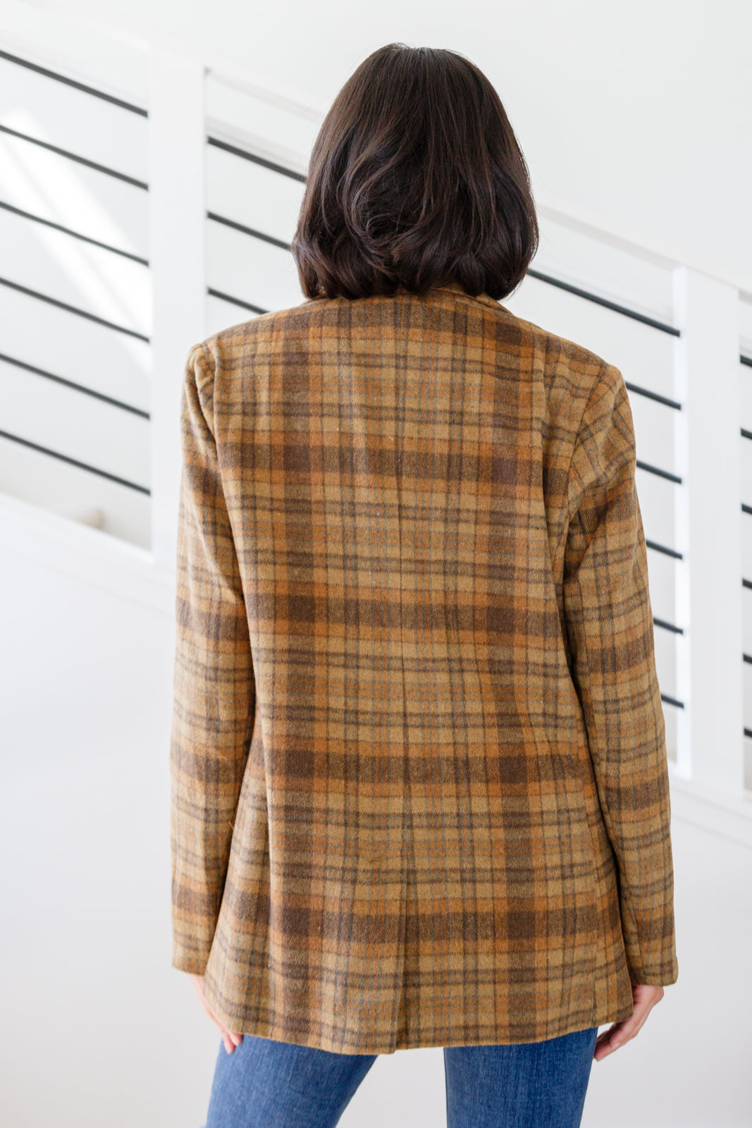 Brown plaid blazer with notched lapels, single button closure, and flap pockets. Features shoulder pads, a fully lined interior, and a tailored, relaxed fit.