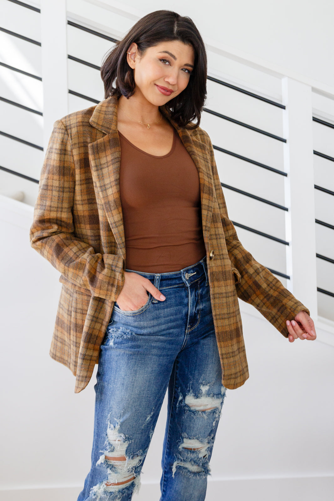 Brown plaid blazer with notched lapels, single button closure, and flap pockets. Features shoulder pads, a fully lined interior, and a tailored, relaxed fit.