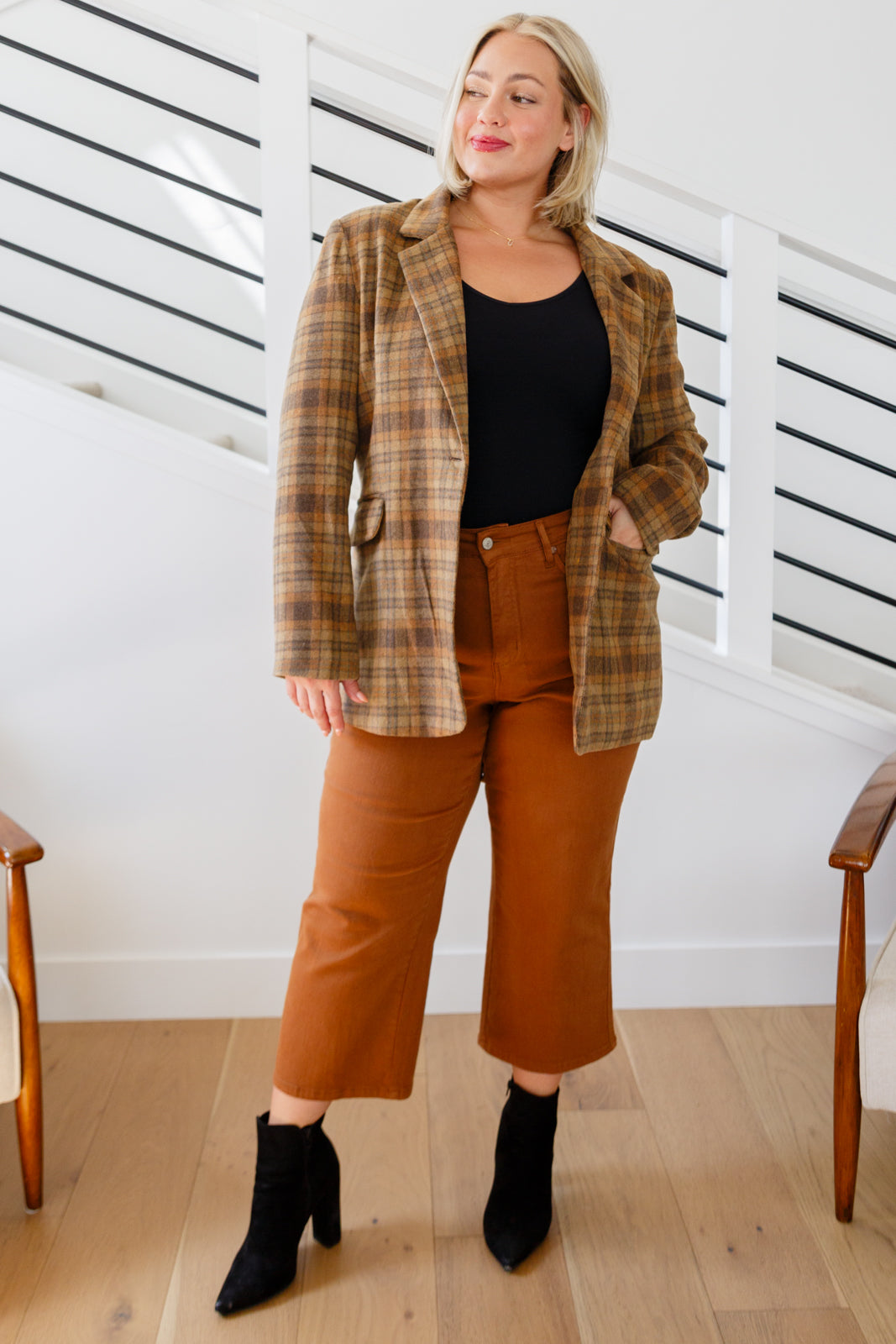 Brown plaid blazer with notched lapels, single button closure, and flap pockets. Features shoulder pads, a fully lined interior, and a tailored, relaxed fit.