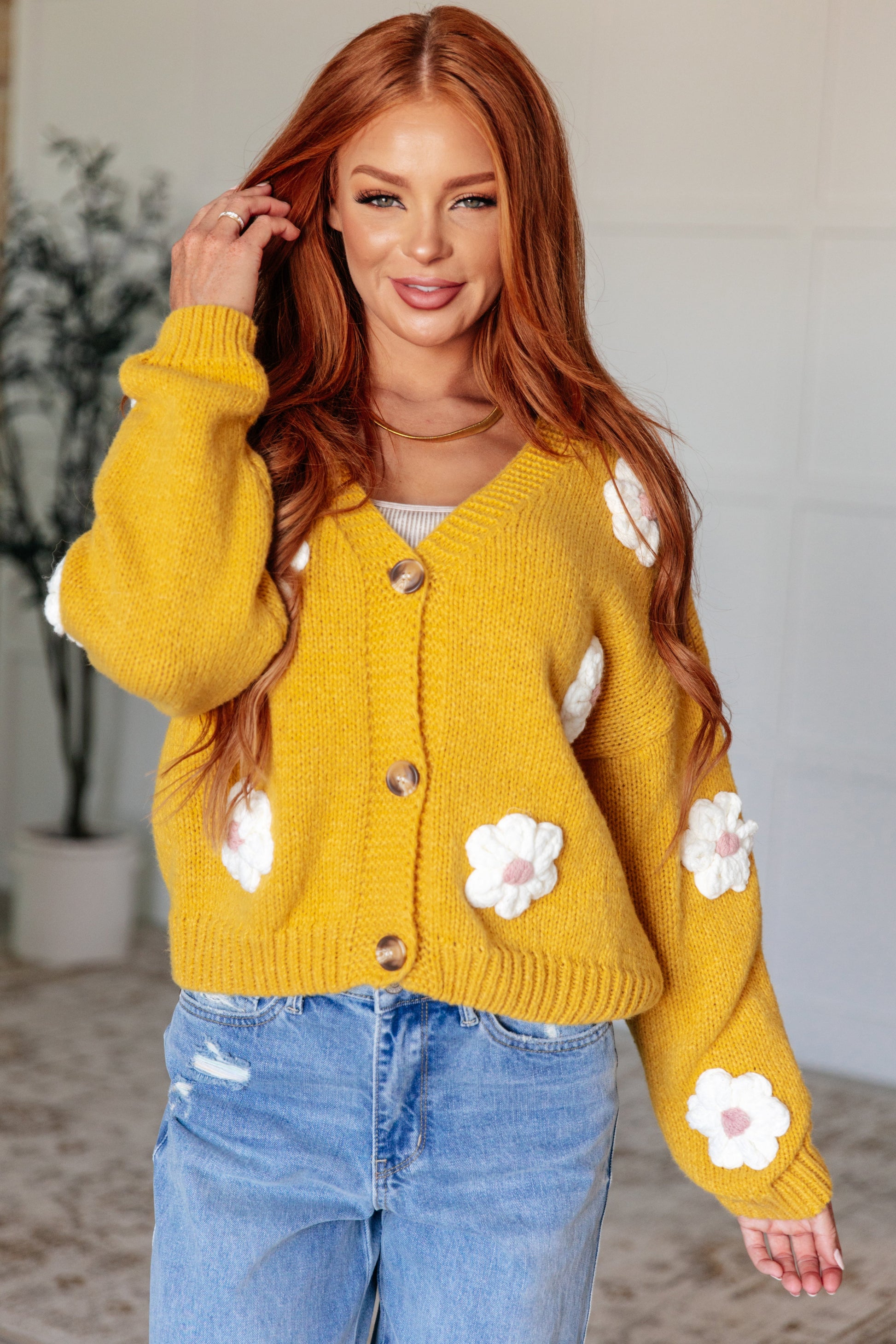 Yellow cardigan with white knit floral accents, V-neck, button front, long sleeves, and drop shoulders.