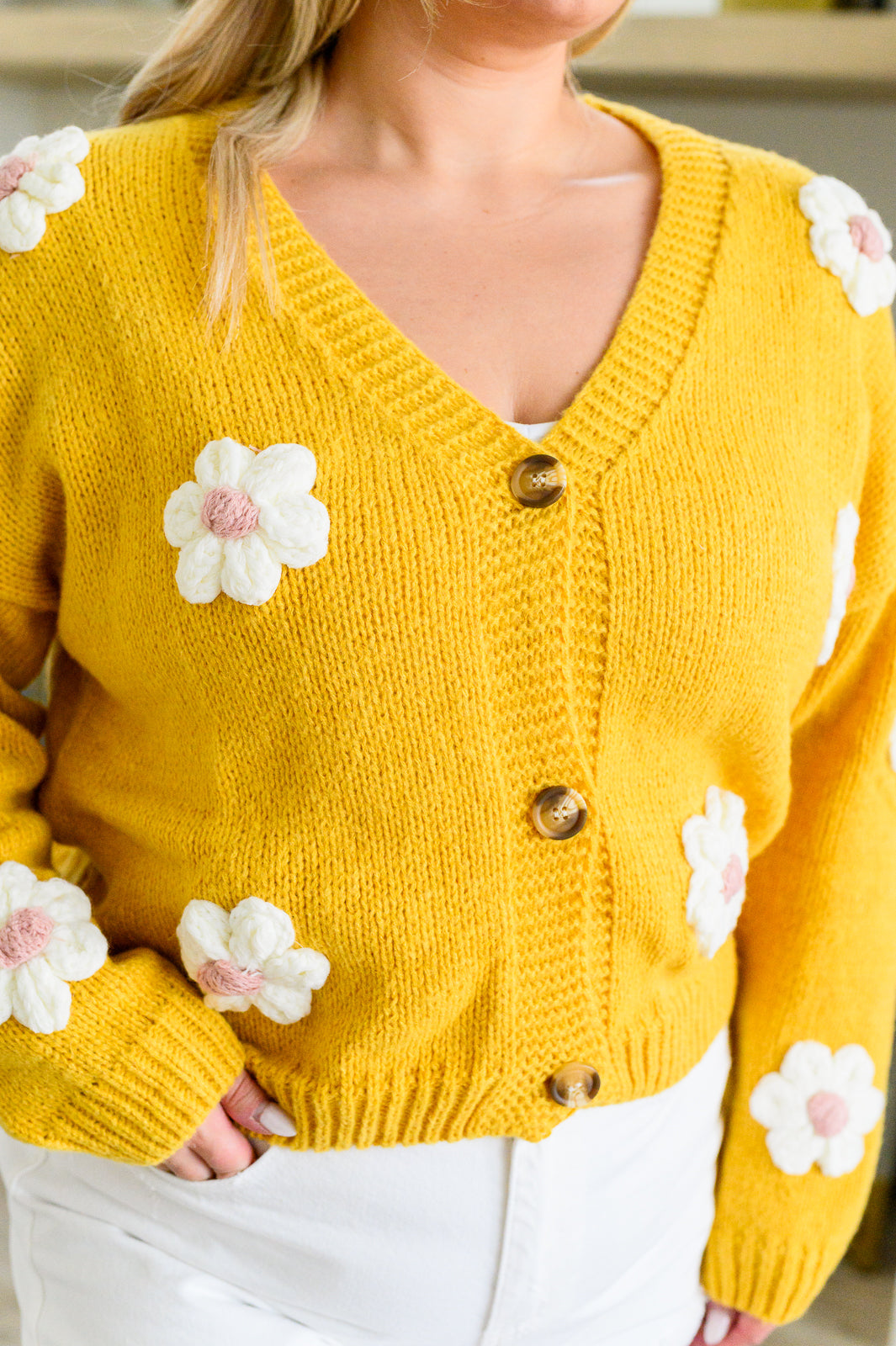 Yellow cardigan with white knit floral accents, V-neck, button front, long sleeves, and drop shoulders.