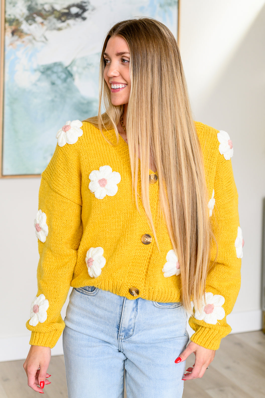 Yellow cardigan with white knit floral accents, V-neck, button front, long sleeves, and drop shoulders.