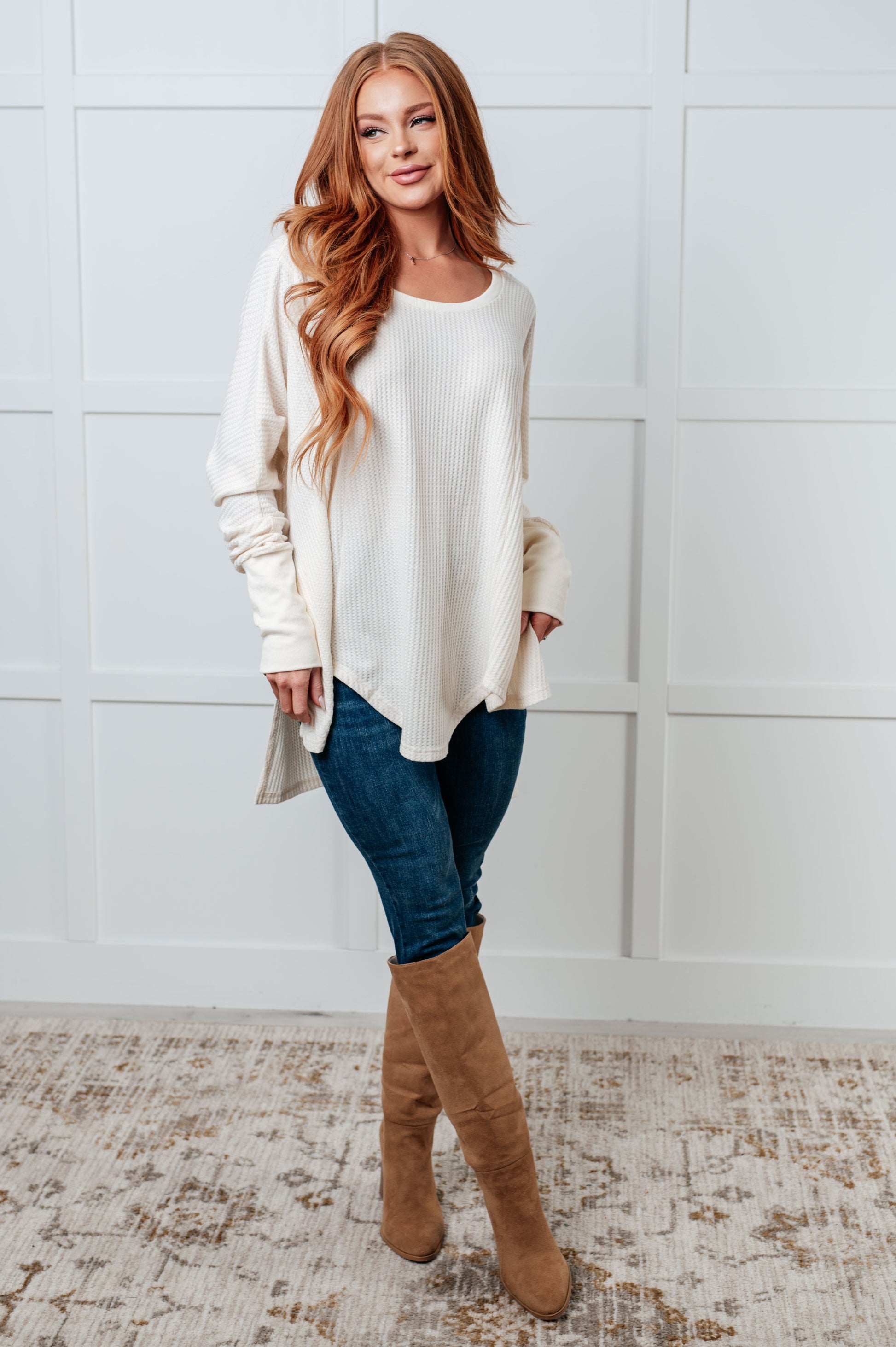 Women's waffle knit shirt with a scoop neckline, long sleeves, exaggerated contrast sleeve cuffs, asymmetrical hemline with side slits, and an oversized fit.