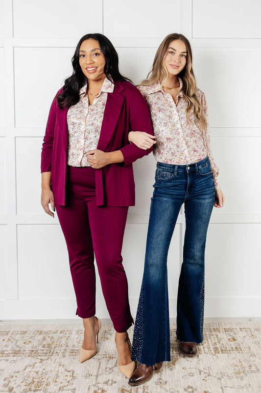 Two models in different sizes wearing Teigan Floral Button Up Blouse with beige chiffon and burgundy floral print.