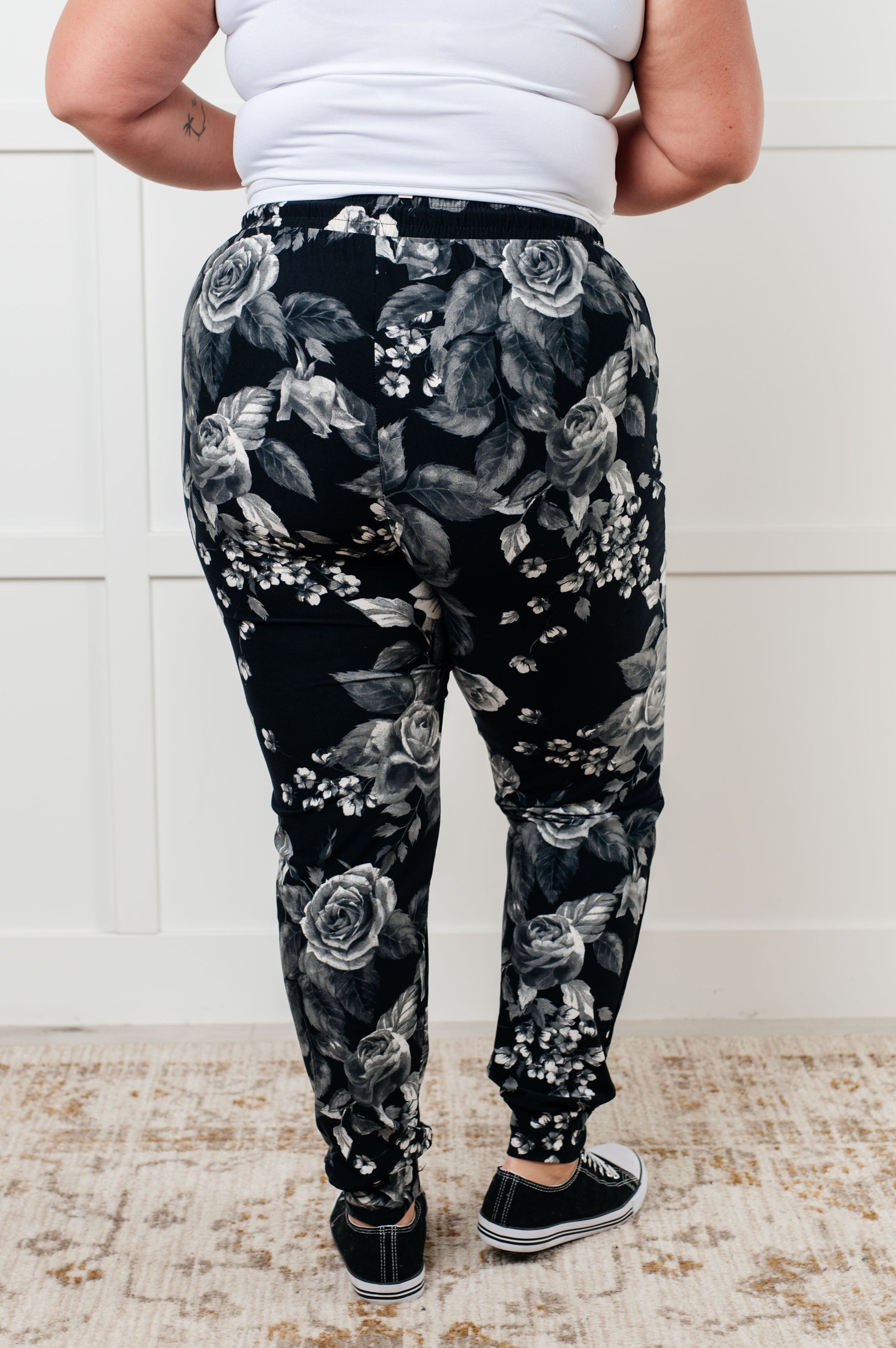 Women's joggers made from brushed microfiber in black with a white rose print, featuring an elastic waistband, functional drawstring, and pockets.