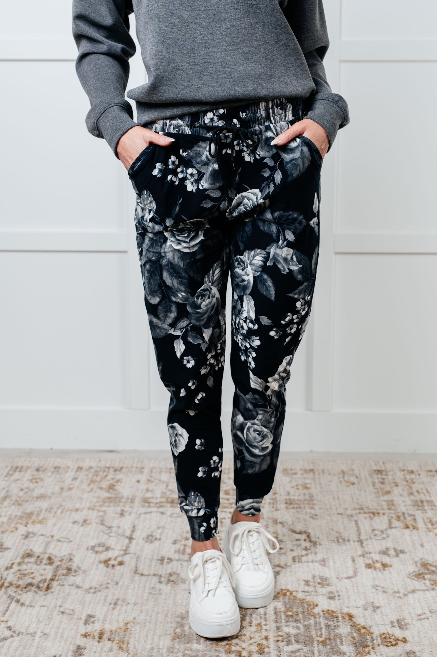 Women's joggers made from brushed microfiber in black with a white rose print, featuring an elastic waistband, functional drawstring, and pockets.