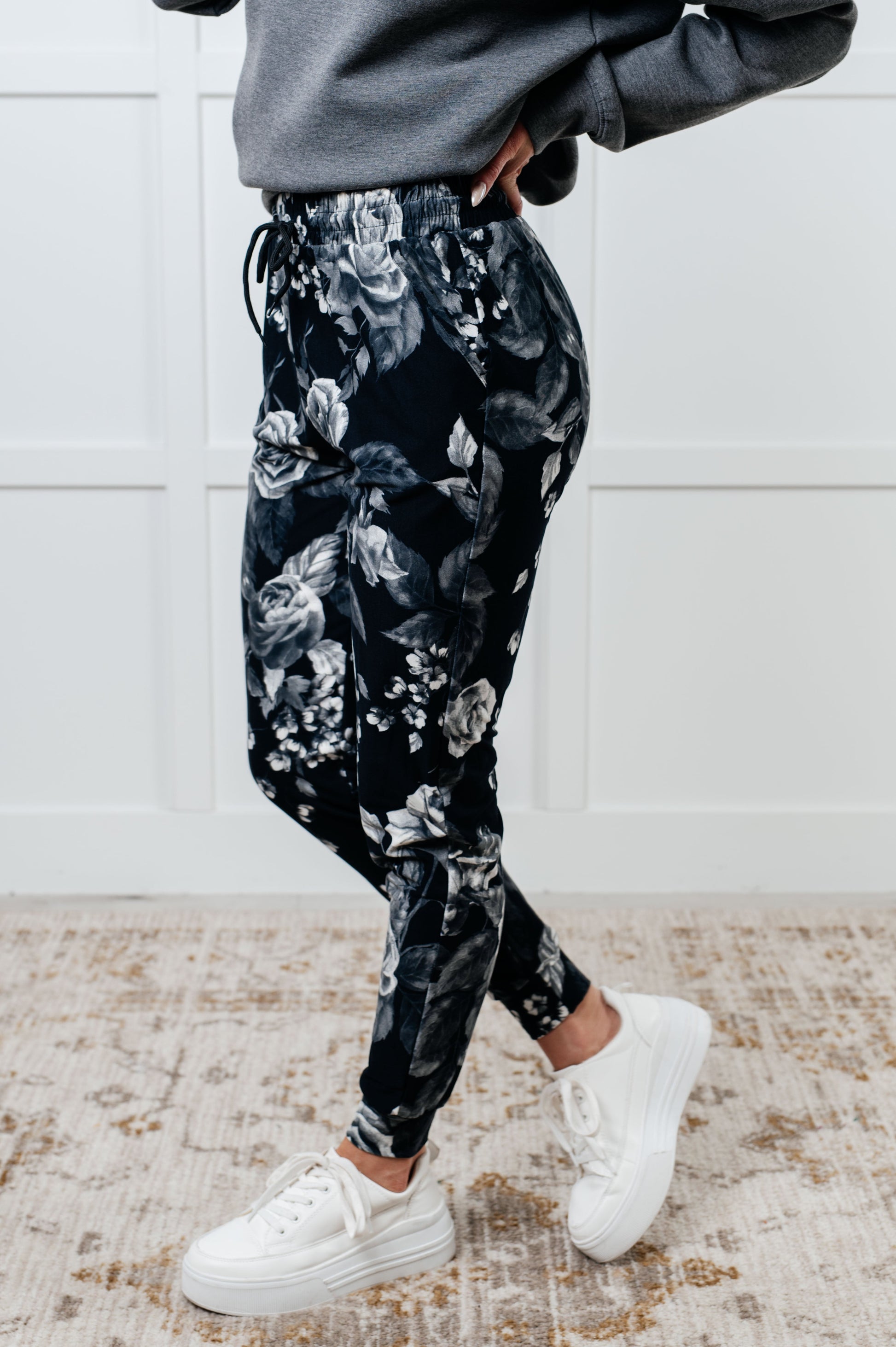 Women's joggers made from brushed microfiber in black with a white rose print, featuring an elastic waistband, functional drawstring, and pockets.