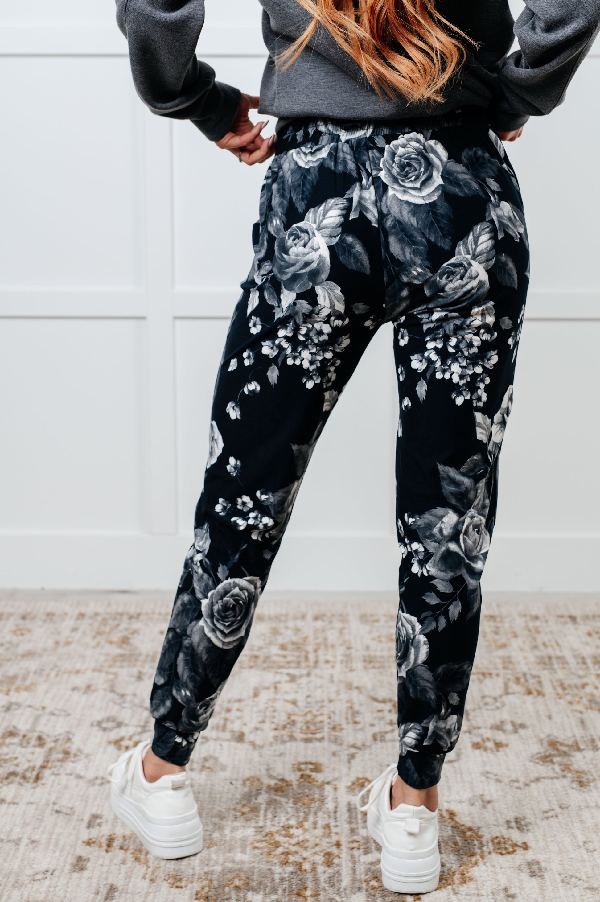 Women's joggers made from brushed microfiber in black with a white rose print, featuring an elastic waistband, functional drawstring, and pockets.