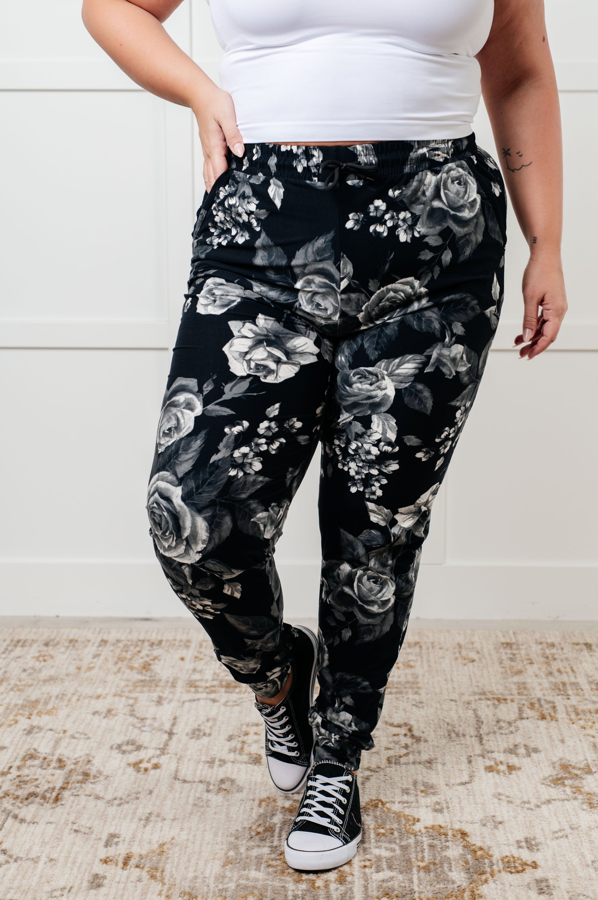 Women's joggers made from brushed microfiber in black with a white rose print, featuring an elastic waistband, functional drawstring, and pockets.