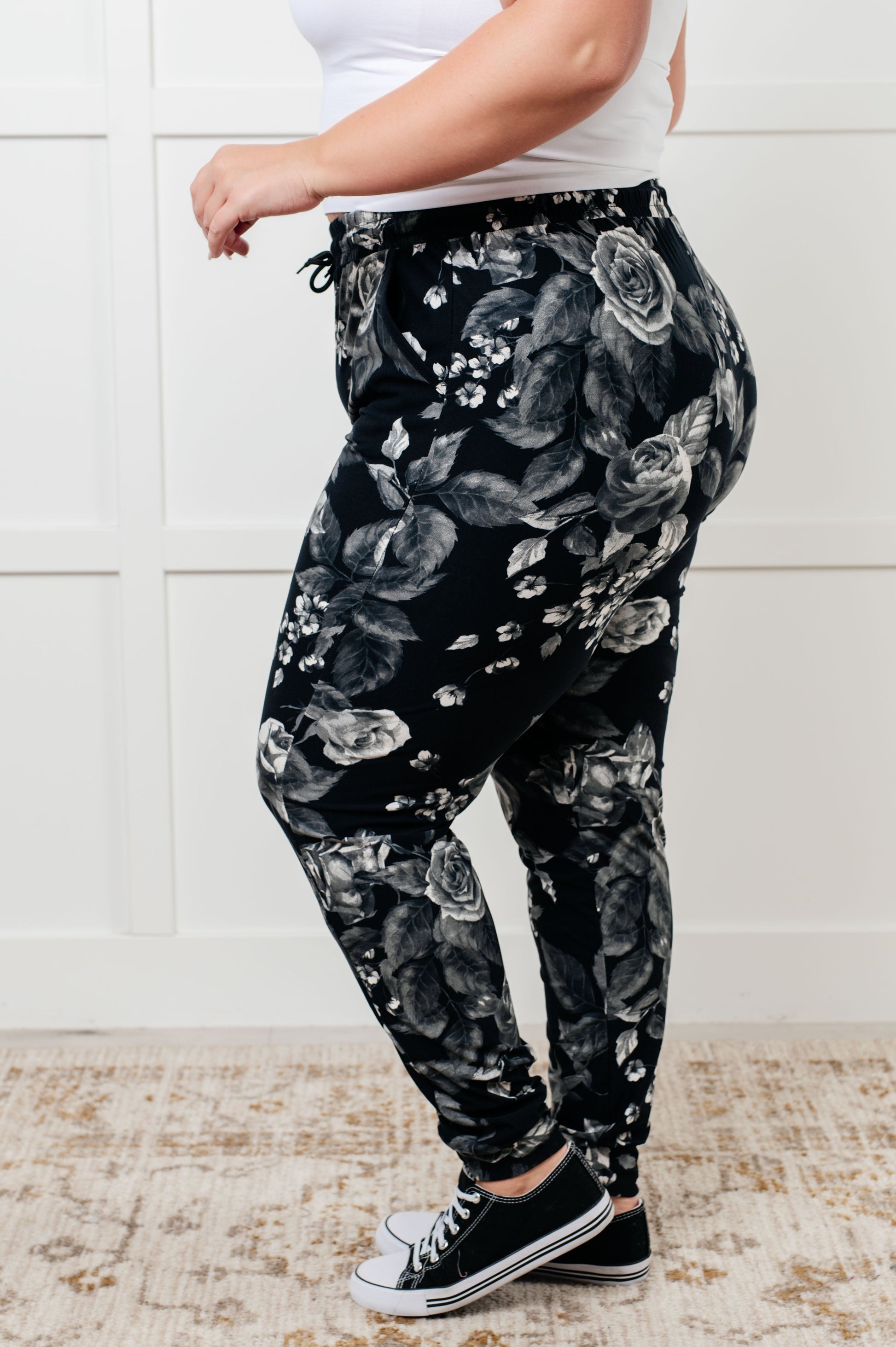 Women's joggers made from brushed microfiber in black with a white rose print, featuring an elastic waistband, functional drawstring, and pockets.