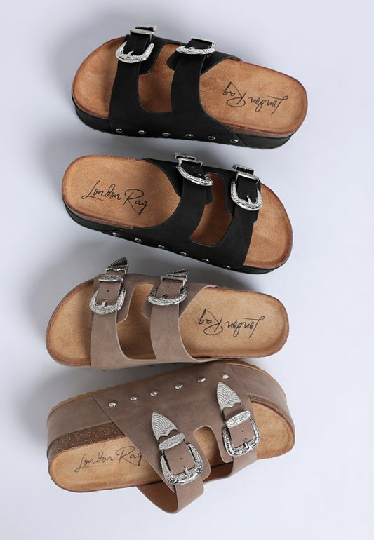 Faux leather flatform slip ons with carved buckle straps and round open toe - available in black and taupe.