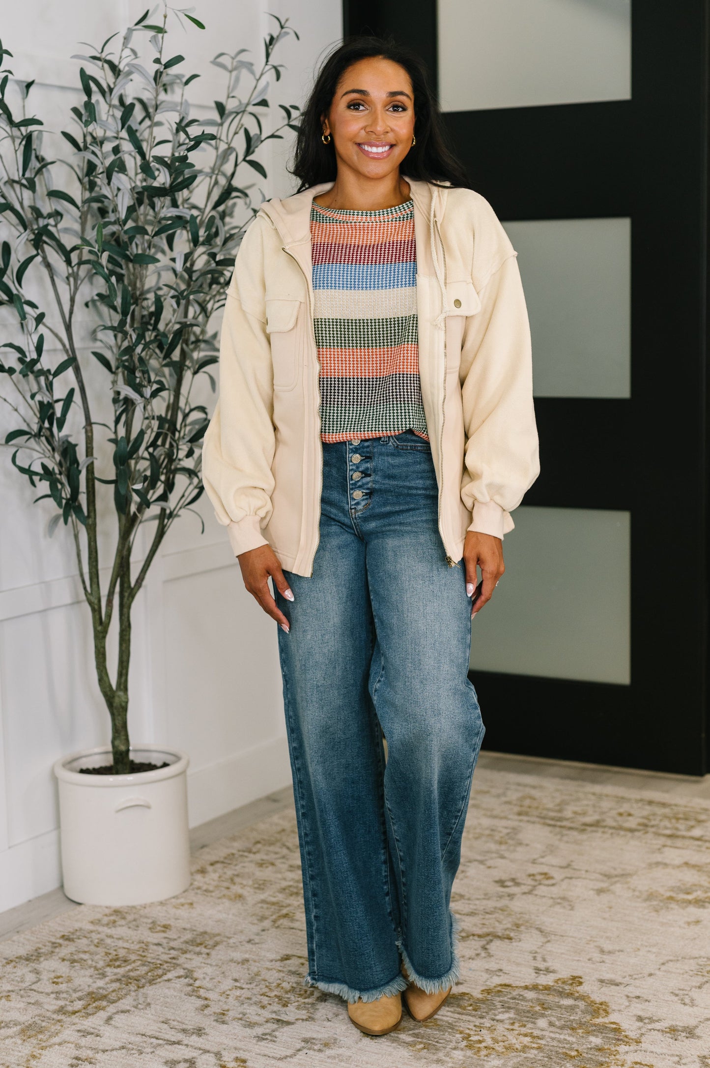 Woman wearing cream Leona Zip-Up Hoodie zipped up with jeans.