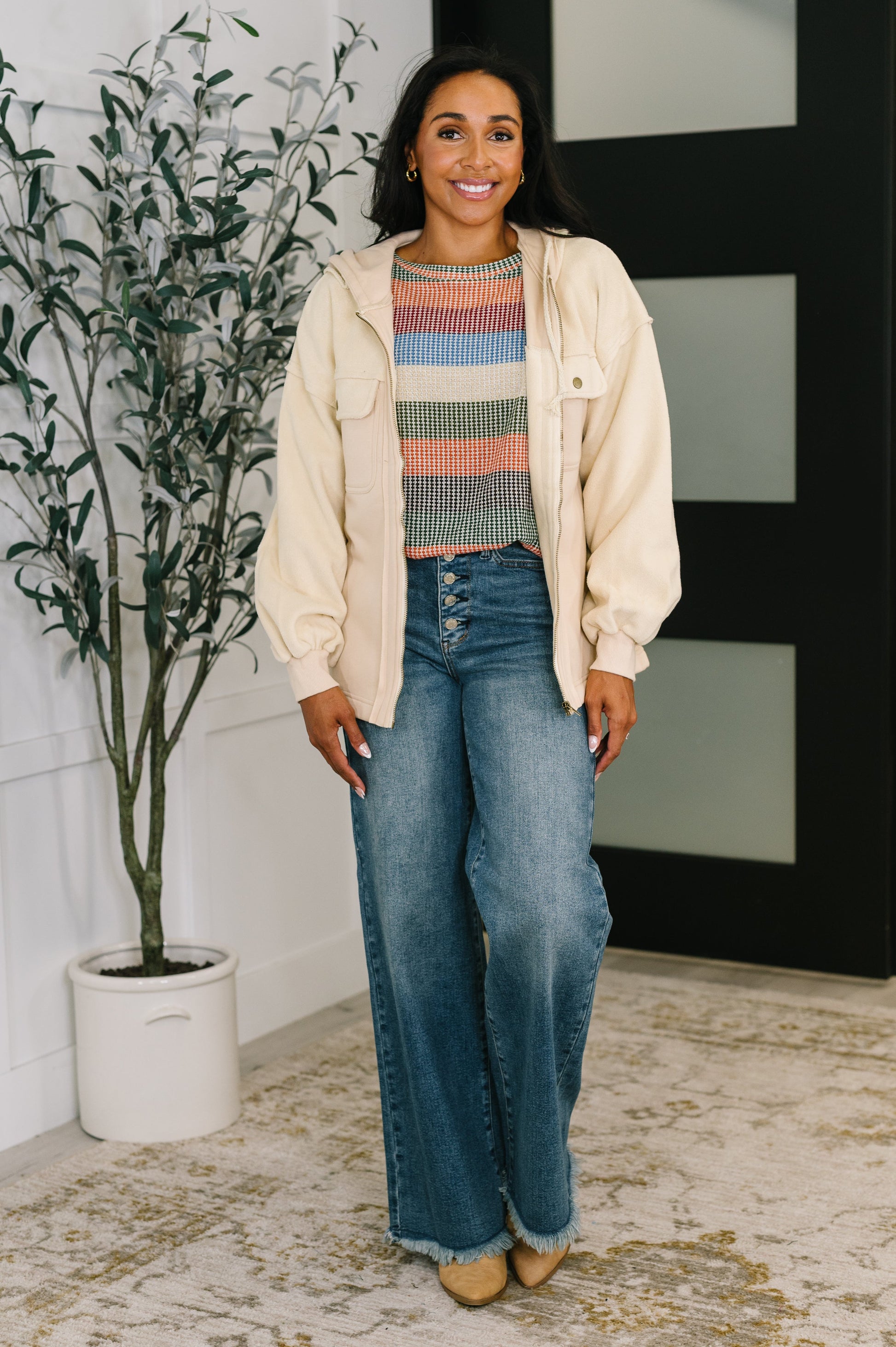 Woman wearing cream Leona Zip-Up Hoodie zipped up with jeans.