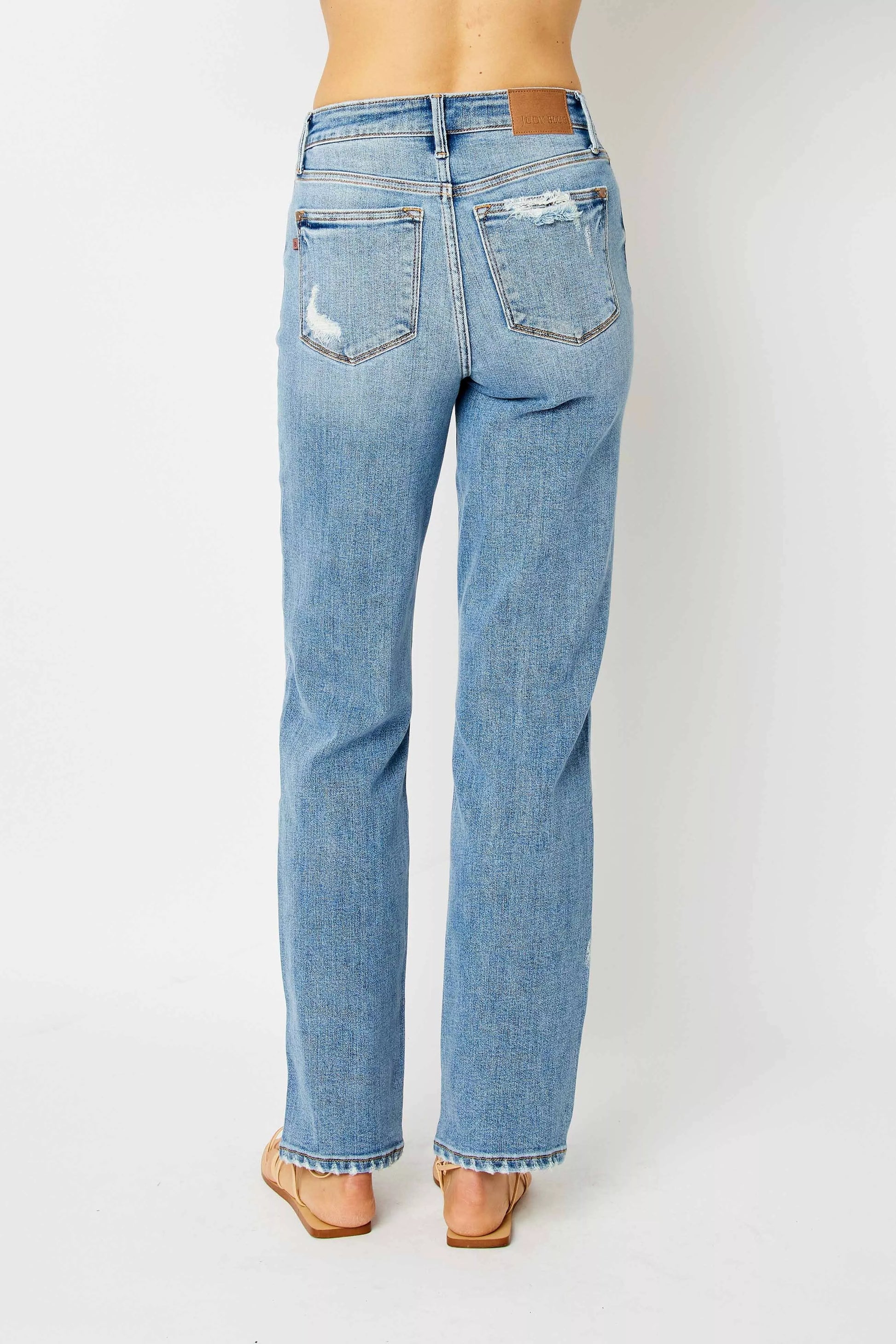 Back view medium wash Estee straight jeans, size inclusive high rise style with raw hem.