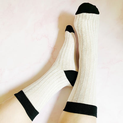 Woman wearing white Silky Jacquard Socks with black trim in a chic, silky jacquard design.