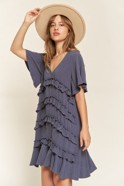 Front view of model wearing Gentry Tiered Ruffle Mini Dress in cement, styled for a casual summer look.