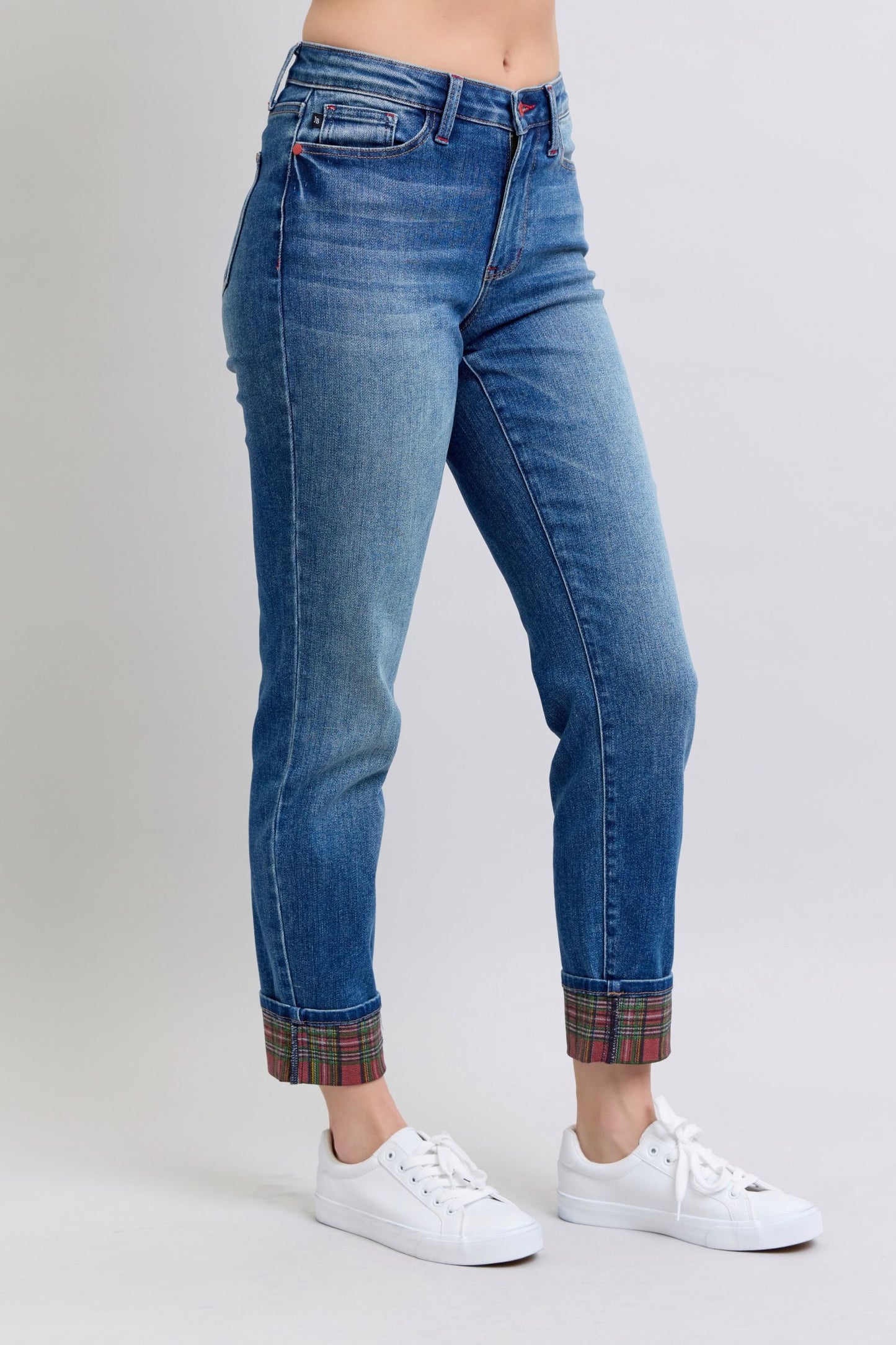 Women's mid rise, medium-wash straight-leg jeans with red and green plaid cuffs.