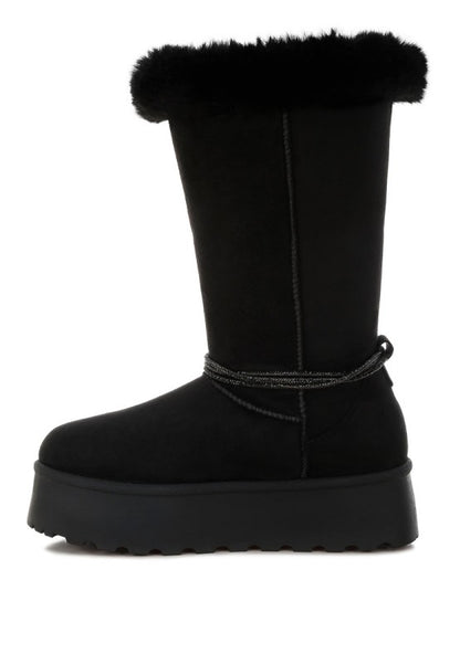 Black boots medial view highlighting side panel seam and fur trim.