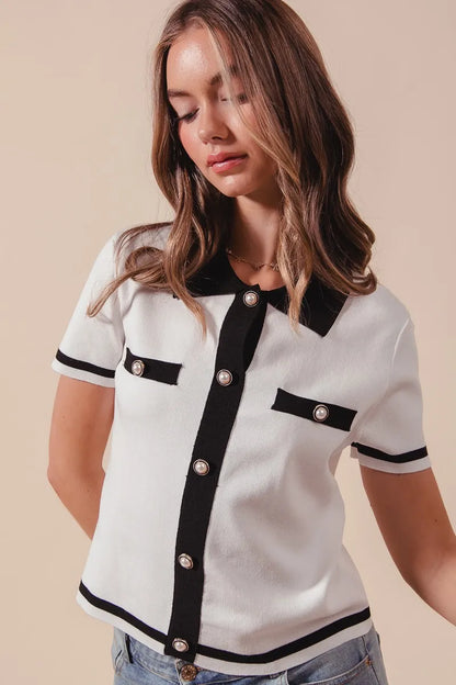 Close-up of Novah ivory knit sweater shirt with textured fabric, black trim, and button accents